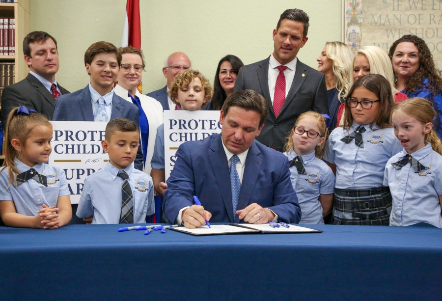 FILE - Florida Gov. Ron DeSantis signs the Parental Rights in Education bill at Classical Preparatory school, March 28, 2022, in Shady Hills, Fla. Top officials at a Florida school district ordered the removal of all books and material containing LBGTQ+ characters and themes from classrooms and campus libraries, saying that was needed to conform to a state law backed by DeSantis that critics have dubbed “Don't Say Gay,” according to a district memo obtained under a public information request by the Florida Freedom to Read Project. The nonprofit group, which opposes the law, provided the memo to The Associated Press on Wednesday, Sept. 27, 2023. (Douglas R. Clifford/Tampa Bay Times via AP, File)