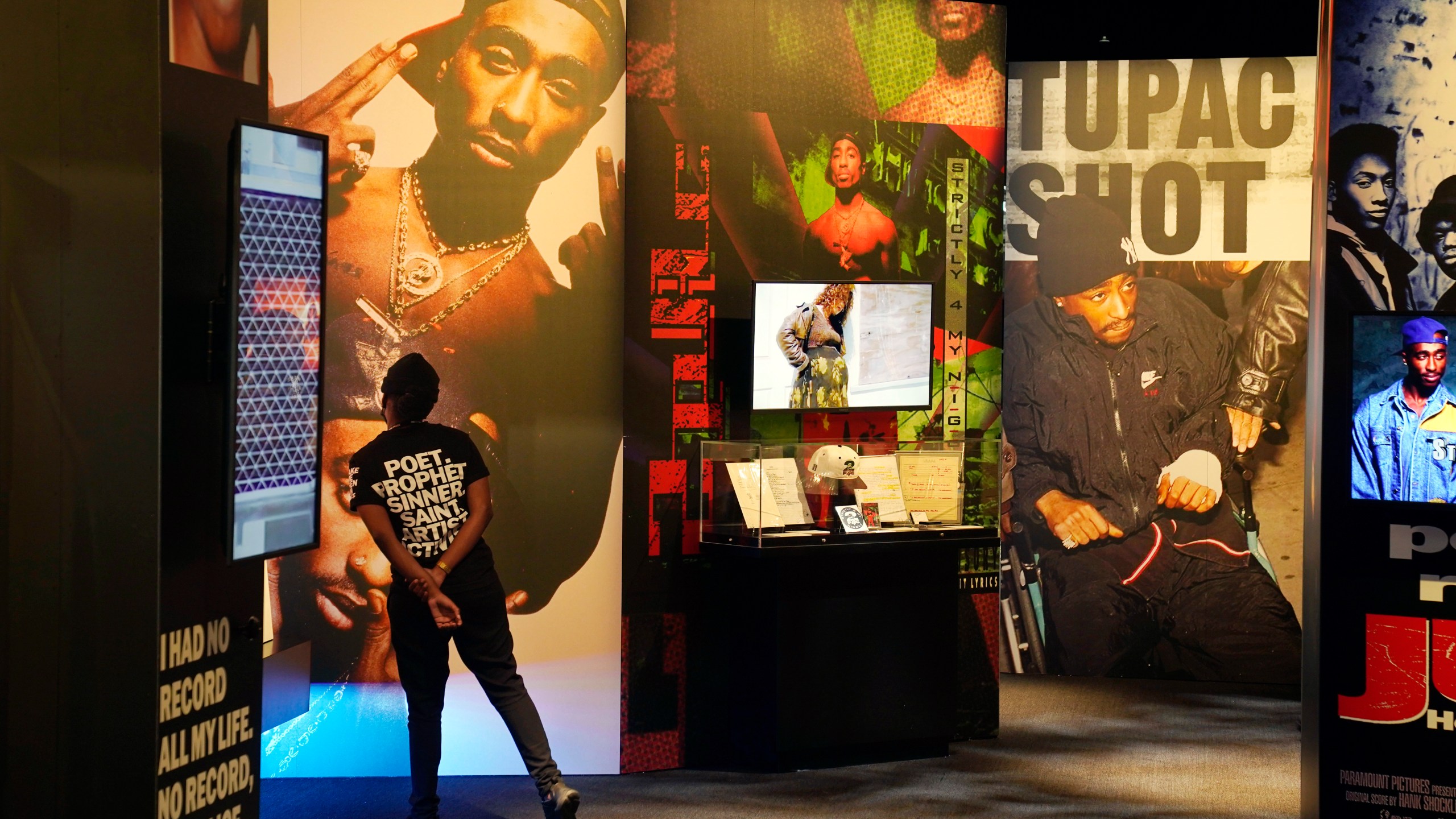 FILE - A visitor observes a display of late hip hop artist Tupac Shakur during the press preview day for the "Tupac Shakur. Wake Me When I'm Free" exhibition, Thursday, Jan. 20, 2022, at The Canvas at L.A. Live in Los Angeles. The unsolved killing of Shakur has taken a major turn. Duane “Keffe D” Davis was arrested Friday morning, although the exact charge or charges were not immediately clear, according to two officials with first-hand knowledge of the arrest. The renewed activity comes nearly 30 years after Shakur was gunned down on Sept. 7, 1996. (AP Photo/Chris Pizzello, File)