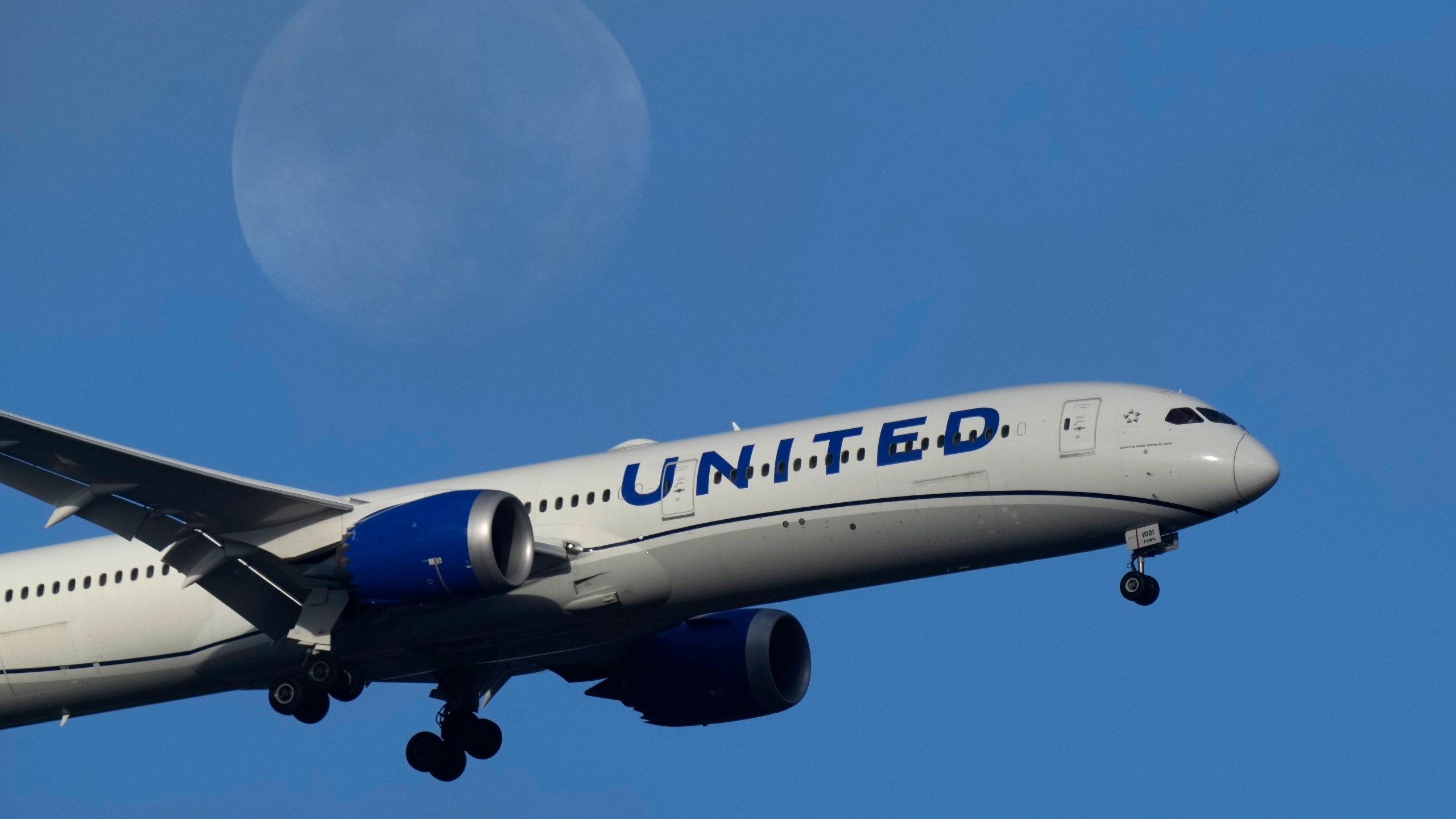 FILE - A United Airlines Boeing 787 approaches for landing in Lisbon, Sept. 2, 2023, with the setting moon in the background. United Airlines is making its second massive order of new planes in less than a year, more than 100 in all, as the carrier renews its fleet. The most recent order announced Tuesday, Oct. 3, will include 50 Boeing 787-9s for delivery between 2028 through 2031, and 60 Airbus A321neos for delivery between 2028 and 2030. (AP Photo/Armando Franca, File)