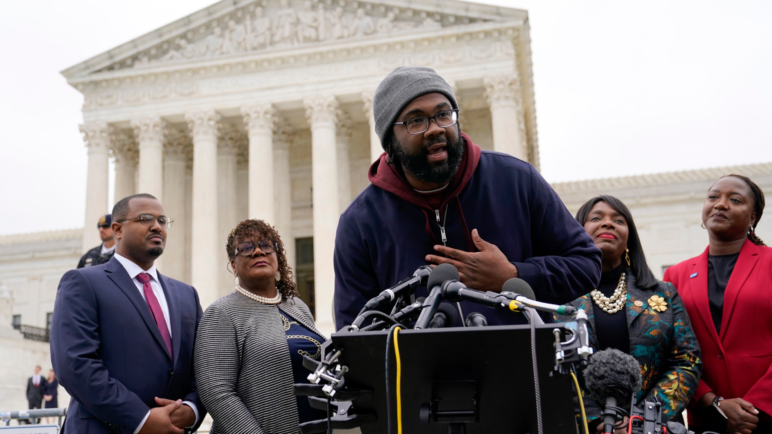 FILE - Evan Milligan, center, plaintiff in Merrill v. Milligan, an Alabama redistricting case speaks with reporters following oral arguments at the Supreme Court in Washington, Oct. 4, 2022. The plaintiffs in voting rights cases in Alabama and Louisiana hoped they would be looking at new maps with additional districts where Black voters might have the opportunity to choose the congress member of their choice. Instead, they are facing continuing fights, including one where Alabama has taken a seemingly oppositional stance to the U.S. Supreme Court's most recent voting rights ruling. (AP Photo/Patrick Semansky, File)