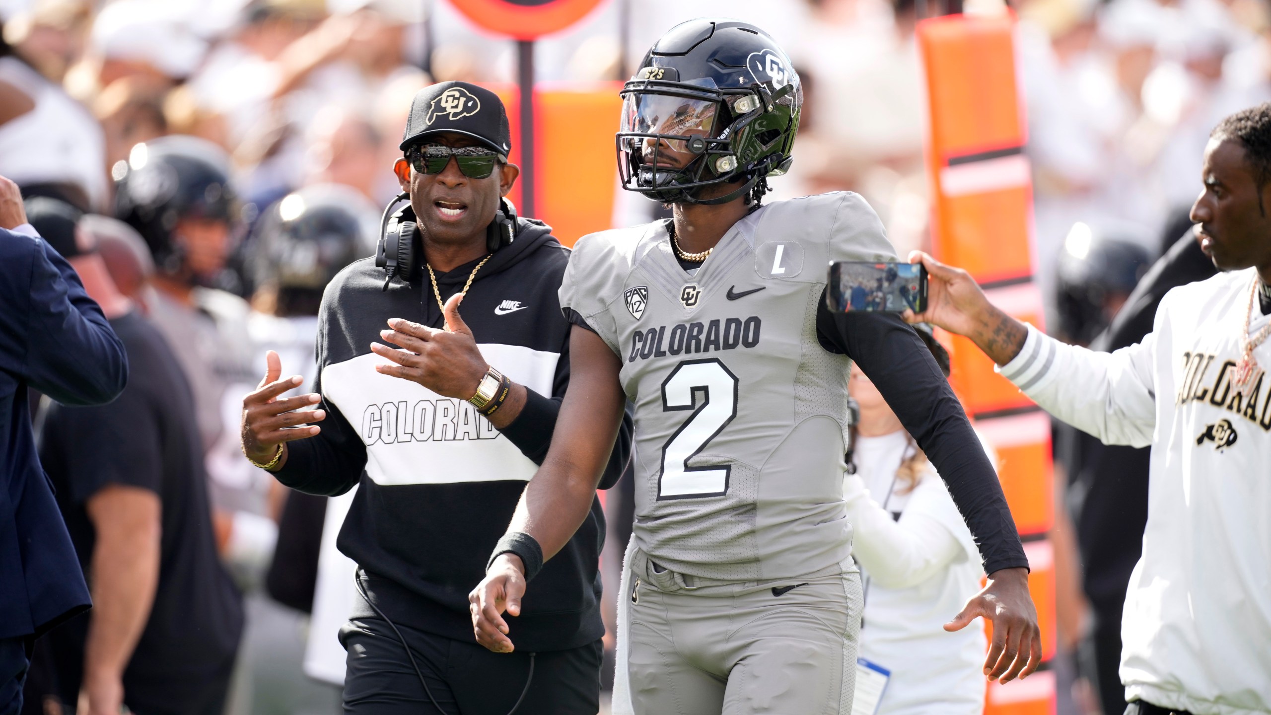 Colorado head coach Deion Sanders, left, talks with his son, quarterback Shedeur Sanders, before the first half of an NCAA college football game against Southern California Saturday, Sept. 30, 2023, in Boulder, Colo. (AP Photo/David Zalubowski)