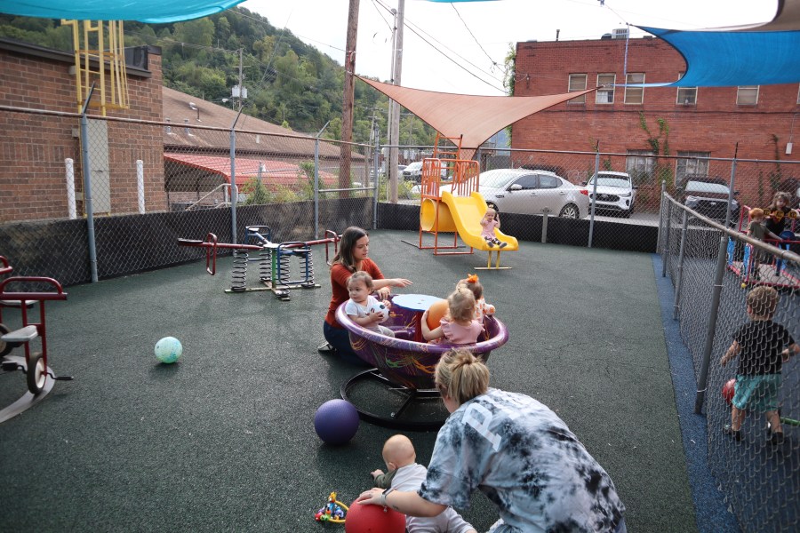 Daycare staff member Caitlyn Hammonds pushes toddlers on a teacup merry-go-round playground toy at Living Water Child Care and Learning Center in Williamson, W.Va. on Monday, Sept. 25, 2023. (AP Photo/Leah Willingham)