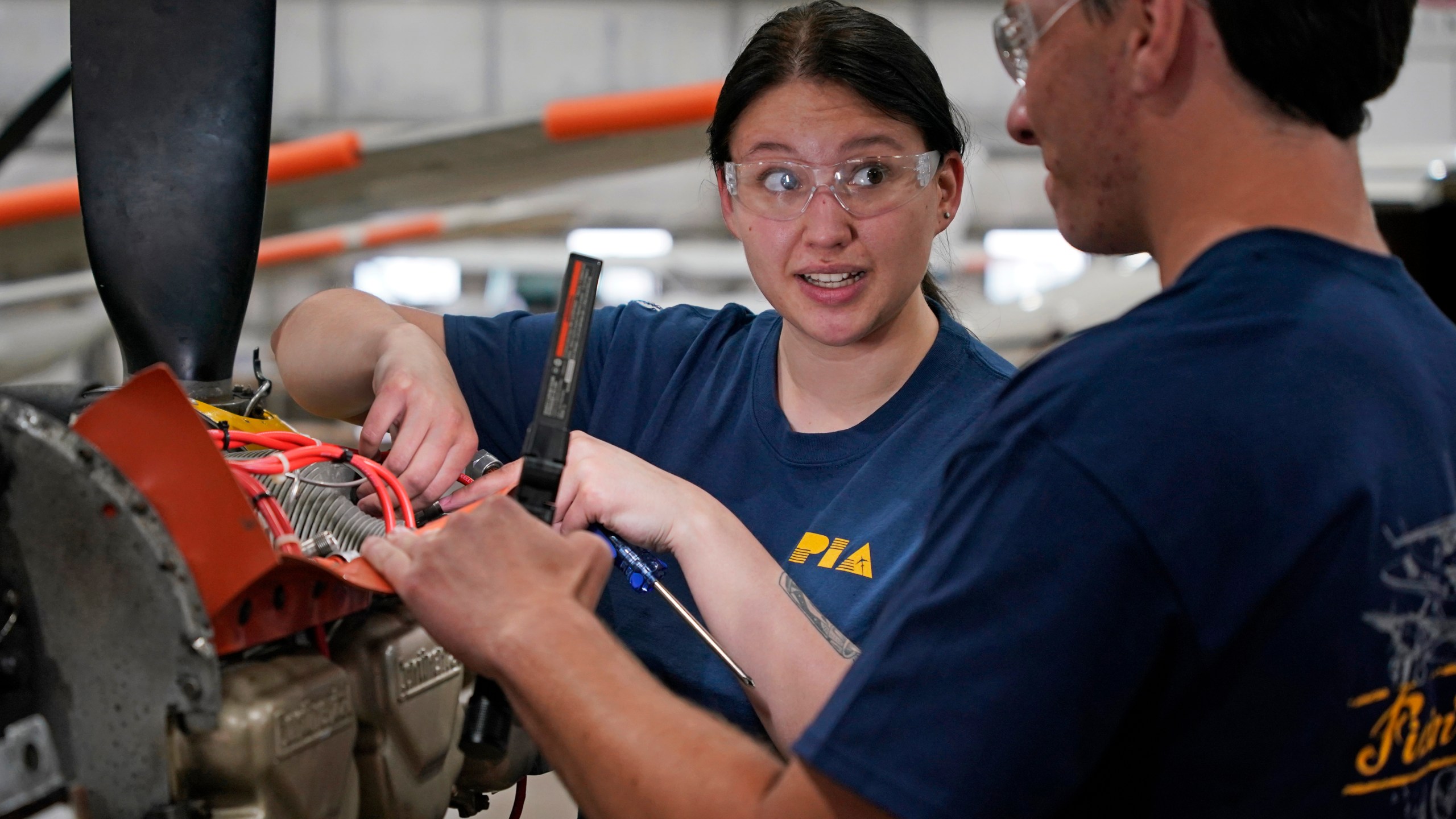 File - Students at the Pittsburgh Institute of Aeronautics Nikki Reed, center, and William Onderdork study the engine on an Cessna 310 aircraft in West Mifflin, Pa., May 2, 2023. On Friday, the U.S. government issues its latest monthly jobs report. (AP Photo/Gene J. Puskar, File)