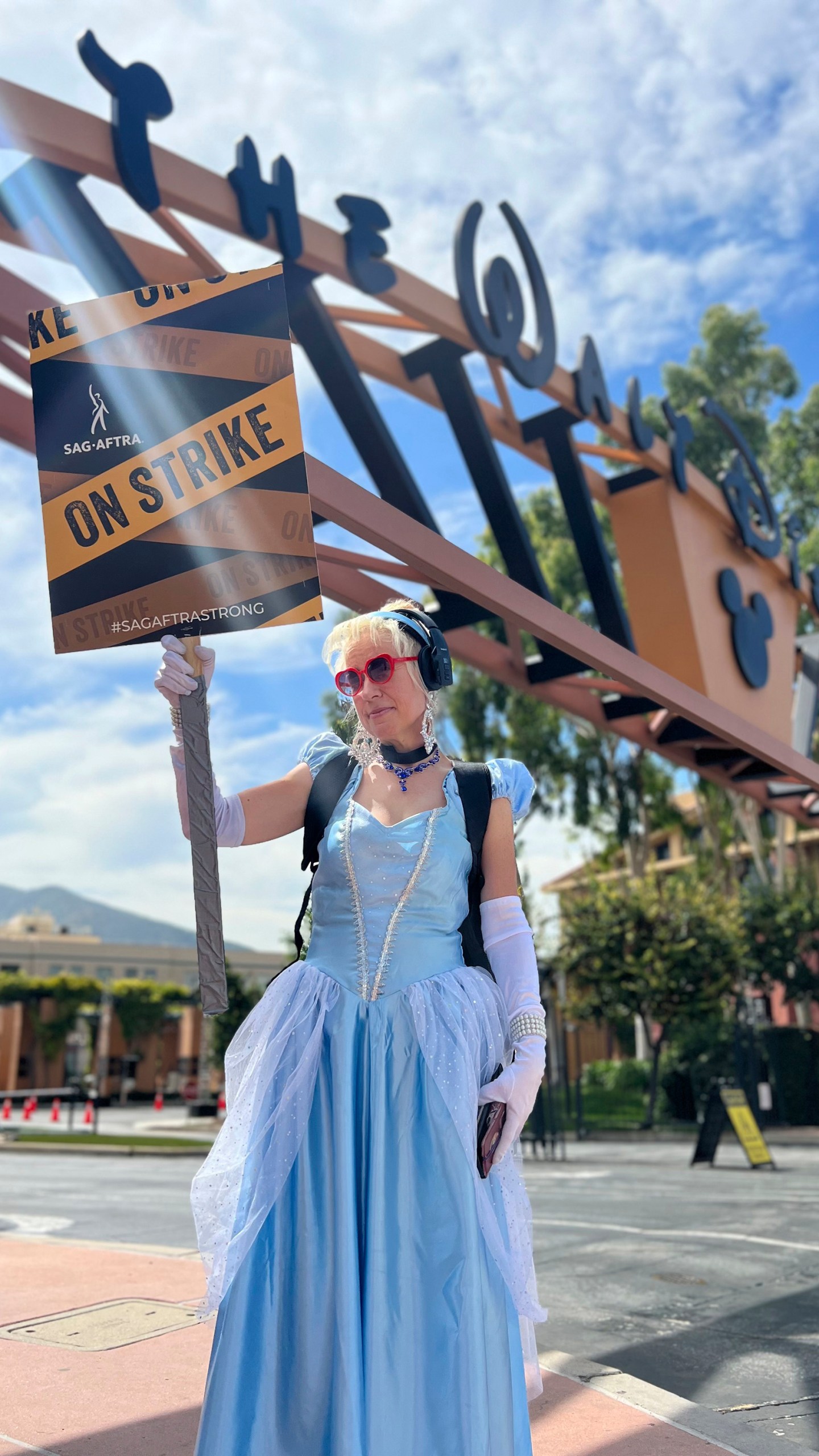 Andrea Calabrese, dressed as the character Cinderella, carries a sign on the picket line outside Walt Disney Studios on Wednesday, Sept. 27, 2023, in Burbank, Calif. Hollywood's writers strike was declared over Tuesday night when board members from their union approved a contract agreement with studios, bringing the industry at least partly back from a historic halt in production. The actors strike continues in their bid to get better pay and working conditions. (AP Photo/Rick Taber)