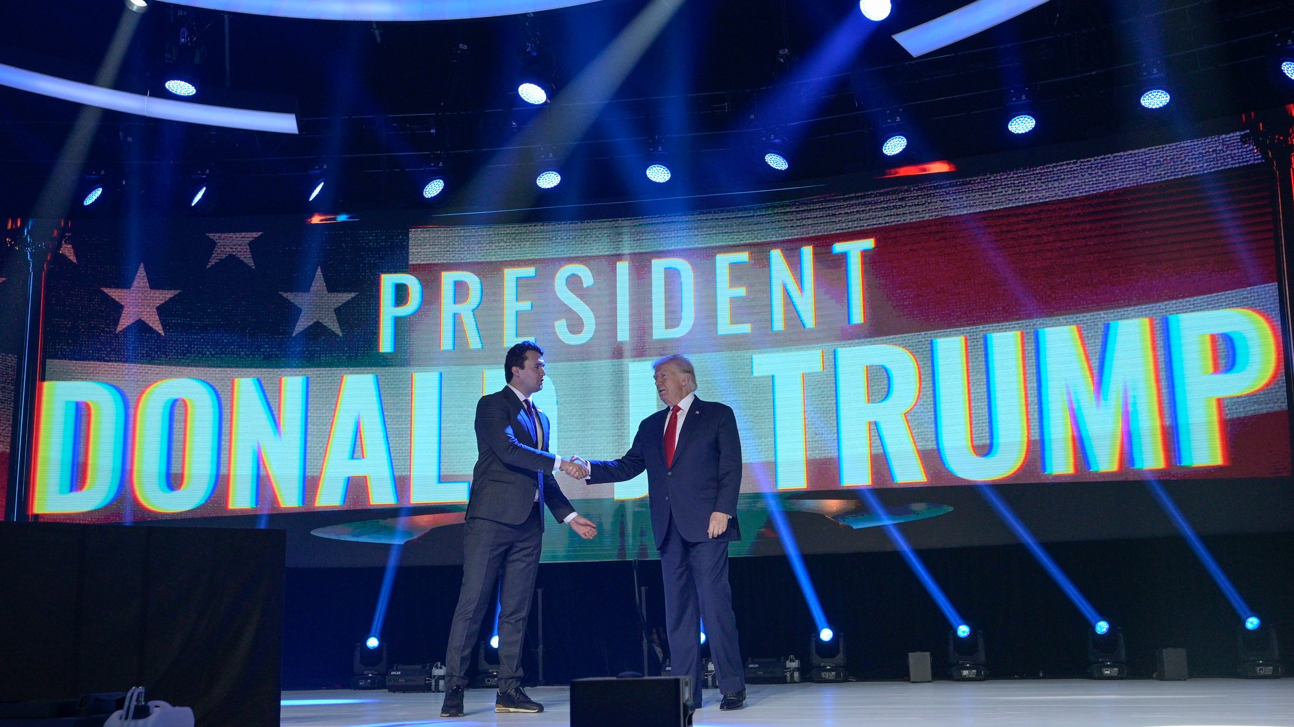 FILE - Former President Donald Trump, right, shakes hands with Turning Point CEO Charlie Kirk before speaking during the Turning Point USA Student Action Summit, July 23, 2022, in Tampa, Fla. The nonprofit rocketed to prominence by latching on to Trump’s 2016 campaign and has raised roughly a quarter-billion dollars since, much of it spent cultivating conservative influencers and hosting glitzy events. The organization also enriched Kirk and his allies, according to an Associated Press review of public records. (AP Photo/Phelan M. Ebenhack, File)