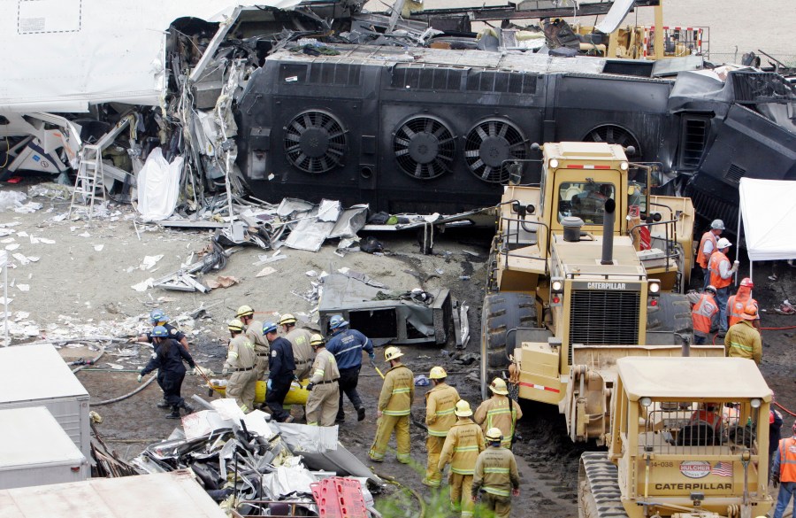 FILE - Emergency responders remove a body from the Metrolink commuter train that collided with a Union Pacific freight train the day before in Chatsworth, Calif., Sept. 13, 2008. Passenger railroads nationwide will now be required to install video recorders inside their locomotives, but the head of the National Transportation Safety Board said the new rule is flawed because it excludes freight trains like the one that derailed and caught fire in eastern Ohio, in February 2023. The NTSB made its recommendation to add cameras in locomotives in 2010 after it investigated the deadly 2008 collision between a Metrolink commuter train and a Union Pacific freight train. (AP Photo/ Rene Macura, File)