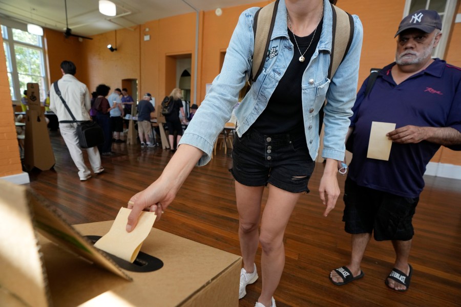 A man, right, waits as a woman drops her ballot into a box a polling place in Redfern as Australians cast their final votes in Sydney, Saturday, Oct. 14, 2023, in their first referendum in a generation that aims to tackle Indigenous disadvantage by enshrining in the constitution a new advocacy committee. Australia will look for new ways to lift Indigenous living standards after voters soundly rejected a proposal to create a new advocacy committee, the deputy prime minister said on Sunday, Oct. 15. (AP Photo/Rick Rycroft, File)