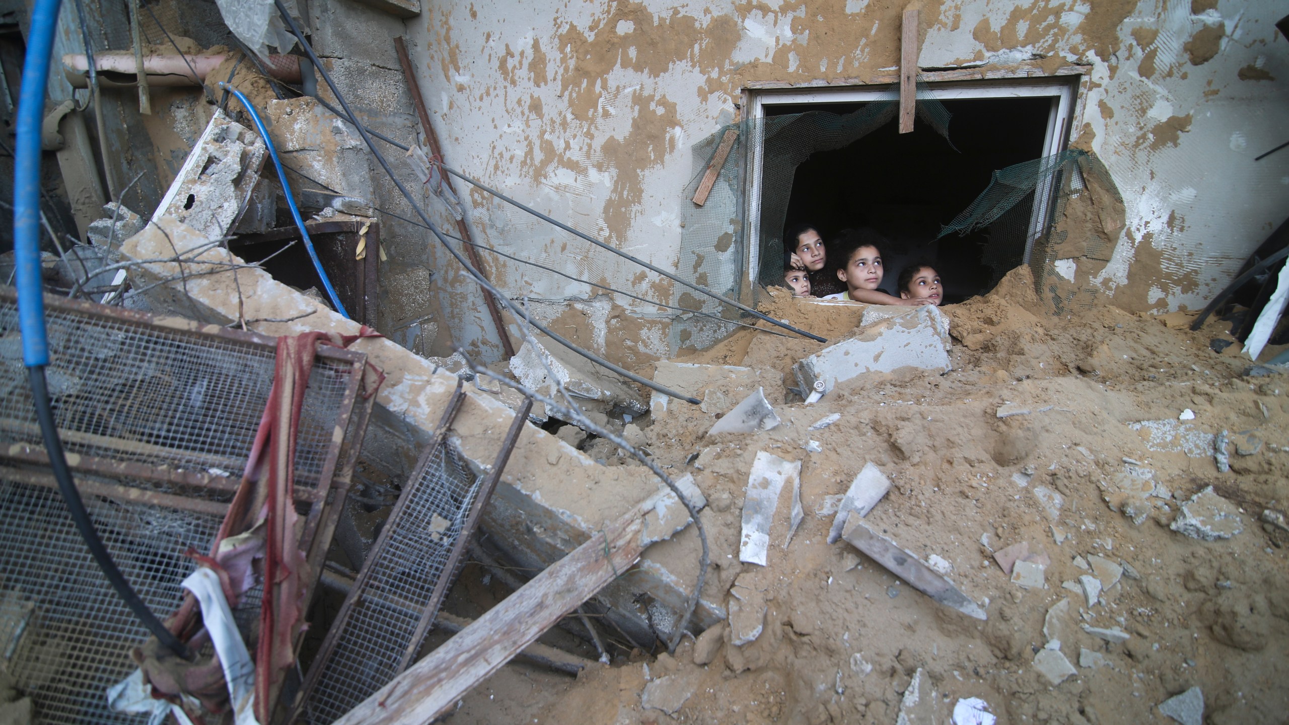 Palestinian children look at the building of the Zanon family, destroyed in Israeli airstrikes in Rafah, Gaza Strip, Saturday, Oct. 14, 2023. (AP Photo/Hatem Ali)