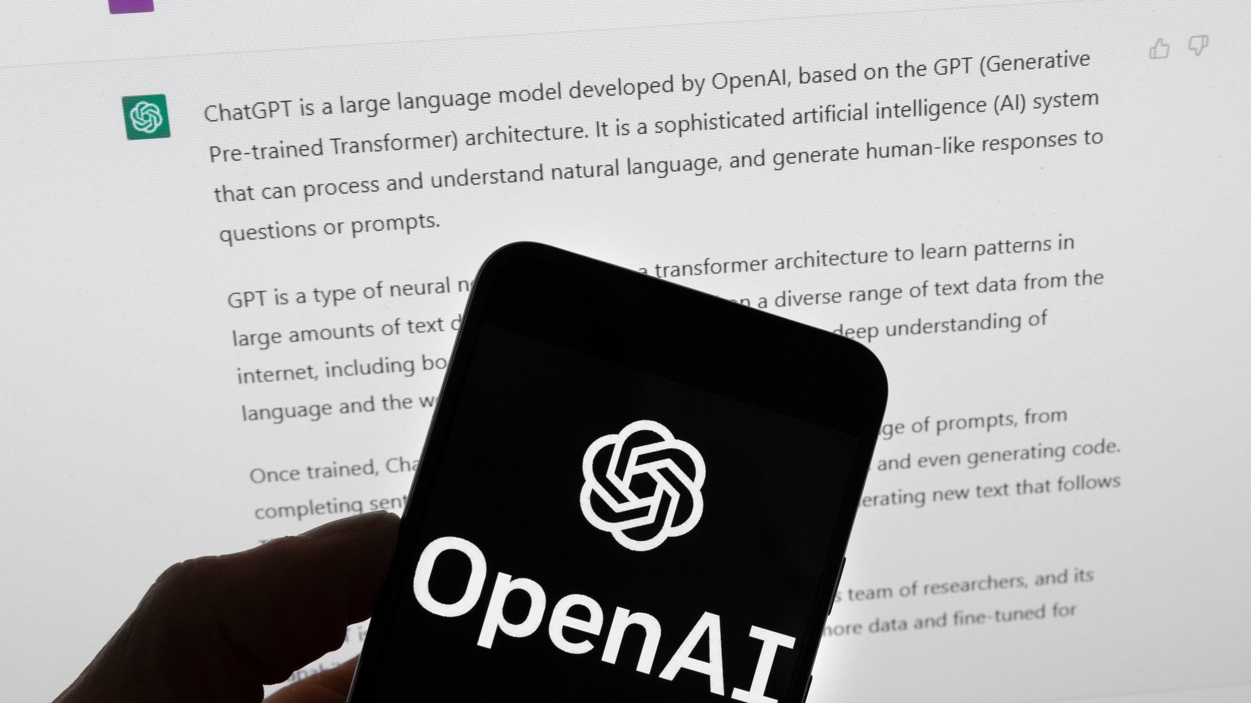 FILE - The OpenAI logo is seen on a mobile phone in front of a computer screen which displays output from ChatGPT, Tuesday, March 21, 2023, in Boston. As schools across the country debate banning AI chatbots in 2023, some math and computer science teachers are embracing them as just another tool. (AP Photo/Michael Dwyer, File)