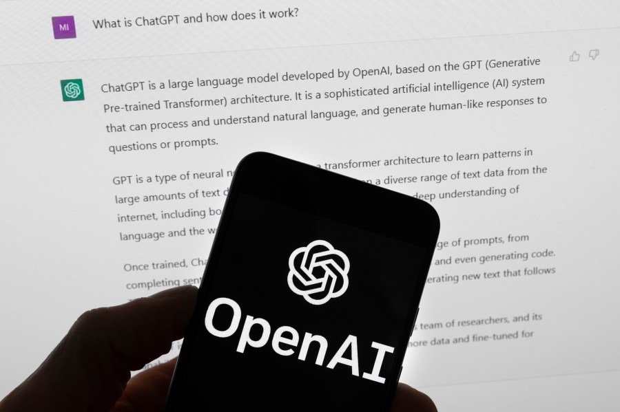 FILE - The OpenAI logo is seen on a mobile phone in front of a computer screen which displays output from ChatGPT, Tuesday, March 21, 2023, in Boston. As schools across the country debate banning AI chatbots in 2023, some math and computer science teachers are embracing them as just another tool. (AP Photo/Michael Dwyer, File)