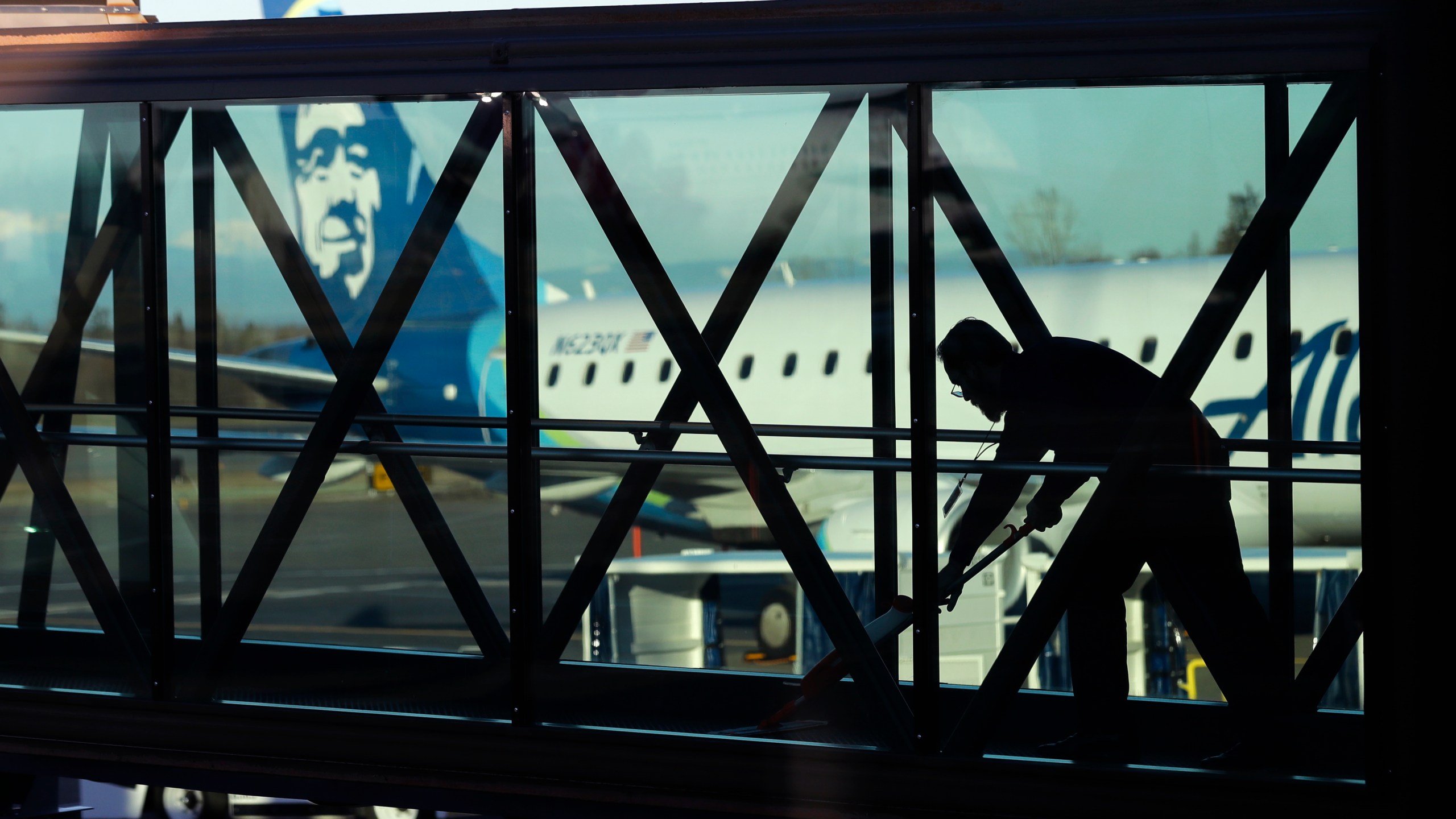 FILE - A worker cleans a jet bridge at Paine Field in Everett, Wash., before passengers board an Alaska Airlines flight on March 4, 2019. Seattle-based Alaska Airlines owns Horizon Air. An off-duty pilot riding in the extra seat in the cockpit of a Horizon Air passenger jet on Sunday, Oct. 22, 2023, tried to shut down the engines in mid-flight and had to be subdued by the crew, according to a pilot flying the plane. (AP Photo/Ted S. Warren, File)