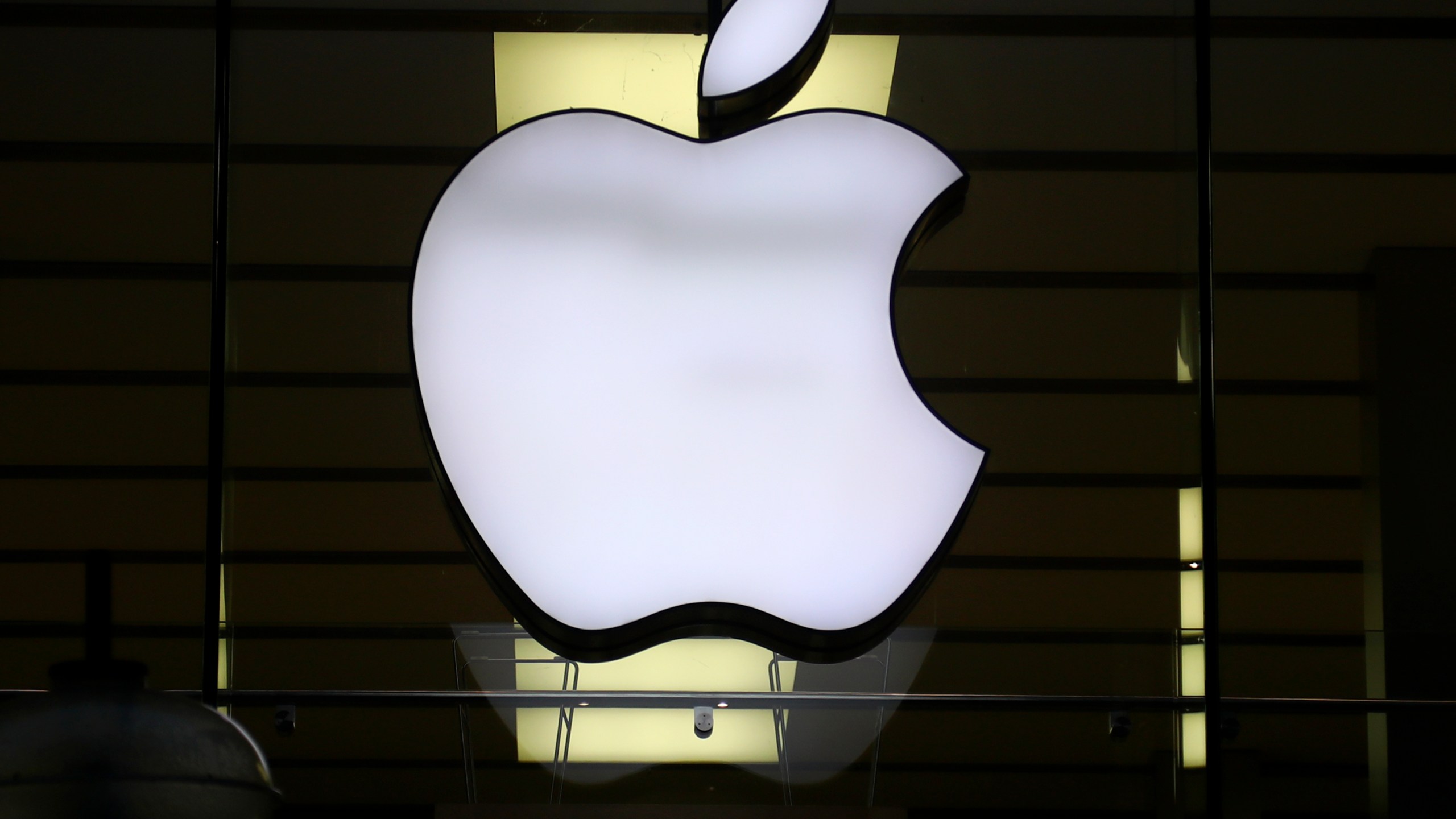 FILE - The Apple logo is illuminated at a store in the city center of Munich, Germany, Dec. 16, 2020. Apple Inc. is raising the prices for its AppleTV+ streaming and Arcade gaming plans, as well as its bundled Apple One service that includes streaming, music and other subscriptions. (AP Photo/Matthias Schrader, File)