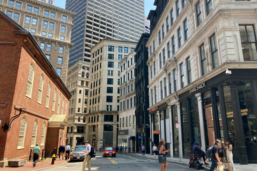 FILE - Pedestrians cross a street, July 11, 2023, in downtown Boston. The Biden administration is launching a multi-agency effort to encourage states and cities to convert more empty office buildings into housing units, with billions of federal dollars available to help spur such transitions. (AP Photo/Steve LeBlanc, File)