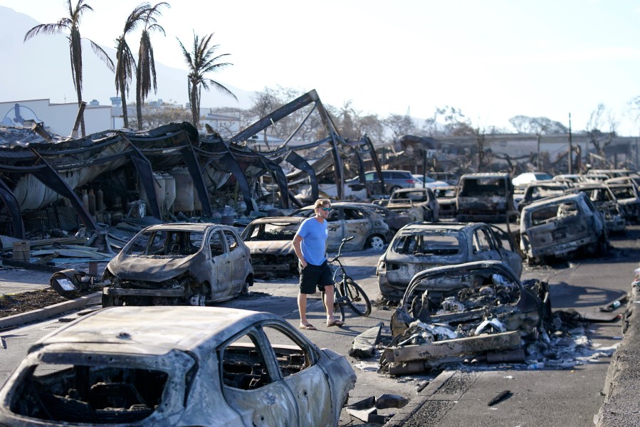 FILE - A man walks through wildfire wreckage in Lahaina, Hawaii, Aug. 11, 2023. Federal authorities have started removing hazardous materials from the Maui wildfires and laying the groundwork to dispose of burnt cars, buildings and other debris. The hazardous materials, including oil, solvent and batteries, are being shipped to the West Coast while the U.S. Army Corps of Engineers works with local officials to develop a plan to dispose of an estimated 400,000 to 700,000 tons of debris on the island. (AP Photo/Rick Bowmer, File)