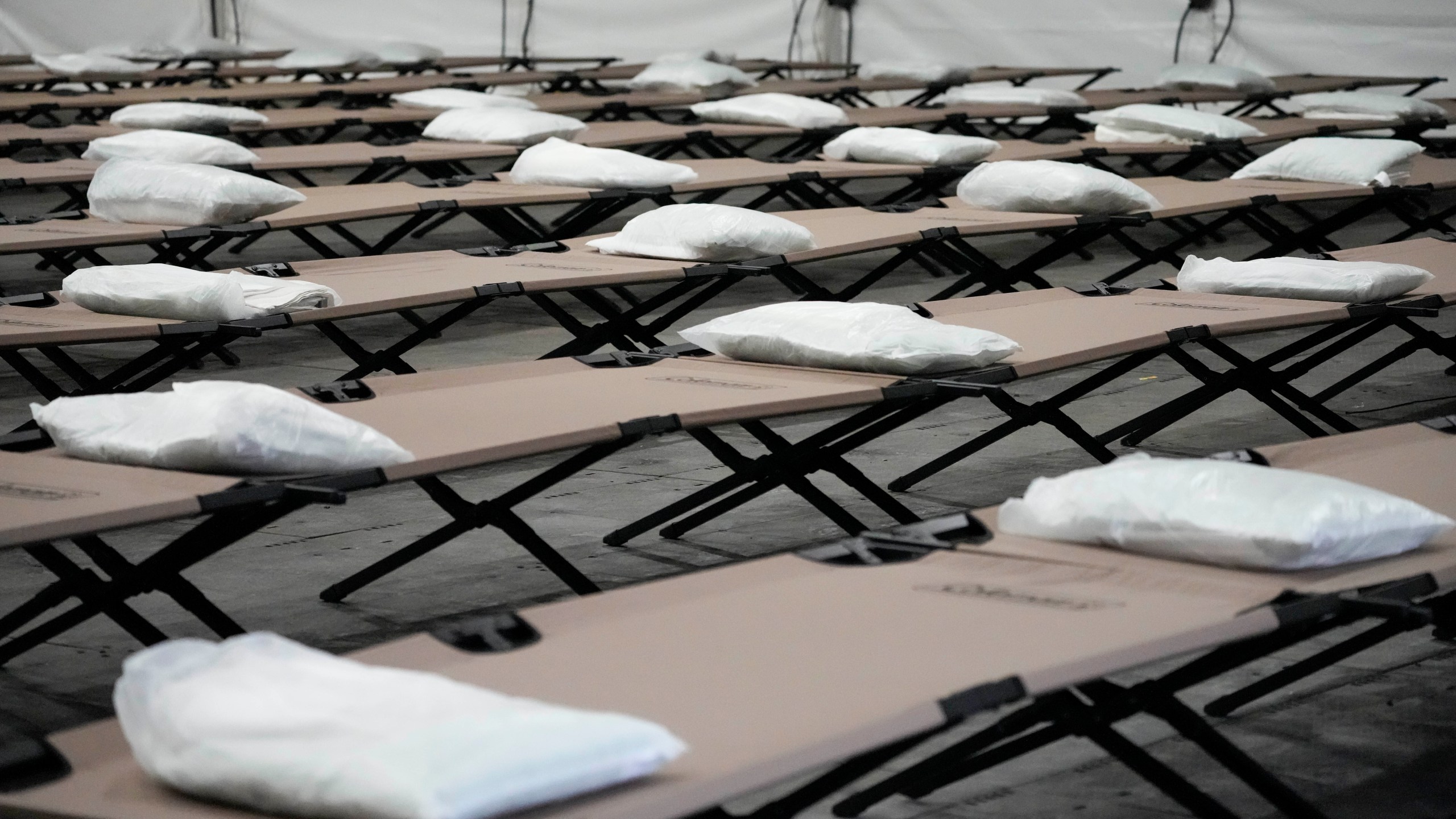 FILE - Bags containing a pillow, towel, and bed sheets are placed on cots inside the dormitory tent during a media tour of a shelter New York City is setting up to house up to 1,000 migrants in the Queens borough of New York, Aug. 15, 2023. Five mayors from around the U.S. want a meeting with President Joe Biden to ask for help controlling the continued arrival of large groups of migrants to their cities. The mayors of Denver, Chicago, Houston, New York and Los Angeles say in a letter to Biden that there has been little to no coordination, support or resources and that is leading to a crisis. (AP Photo/Mary Altaffer, File)