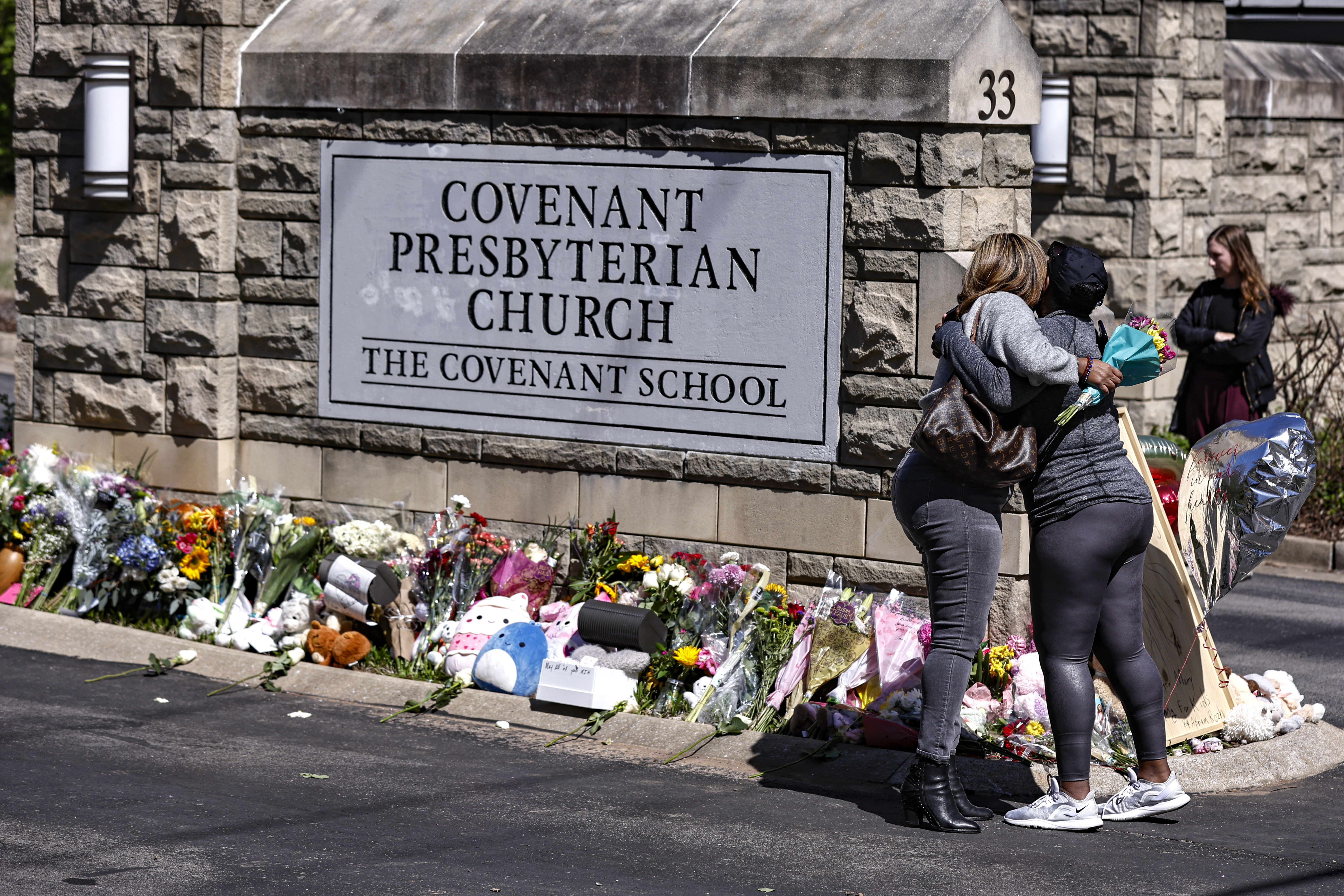 FILE - Two women hug near a memorial at the entrance to The Covenant School, March 29, 2023, in Nashville, Tenn. The Tennessee Court of Appeals heard arguments Monday, Oct. 16, on whether Tennessee law gives the parents of school shooting victims the right to have a say over which police records are released to the public. (AP Photo/Wade Payne, File)