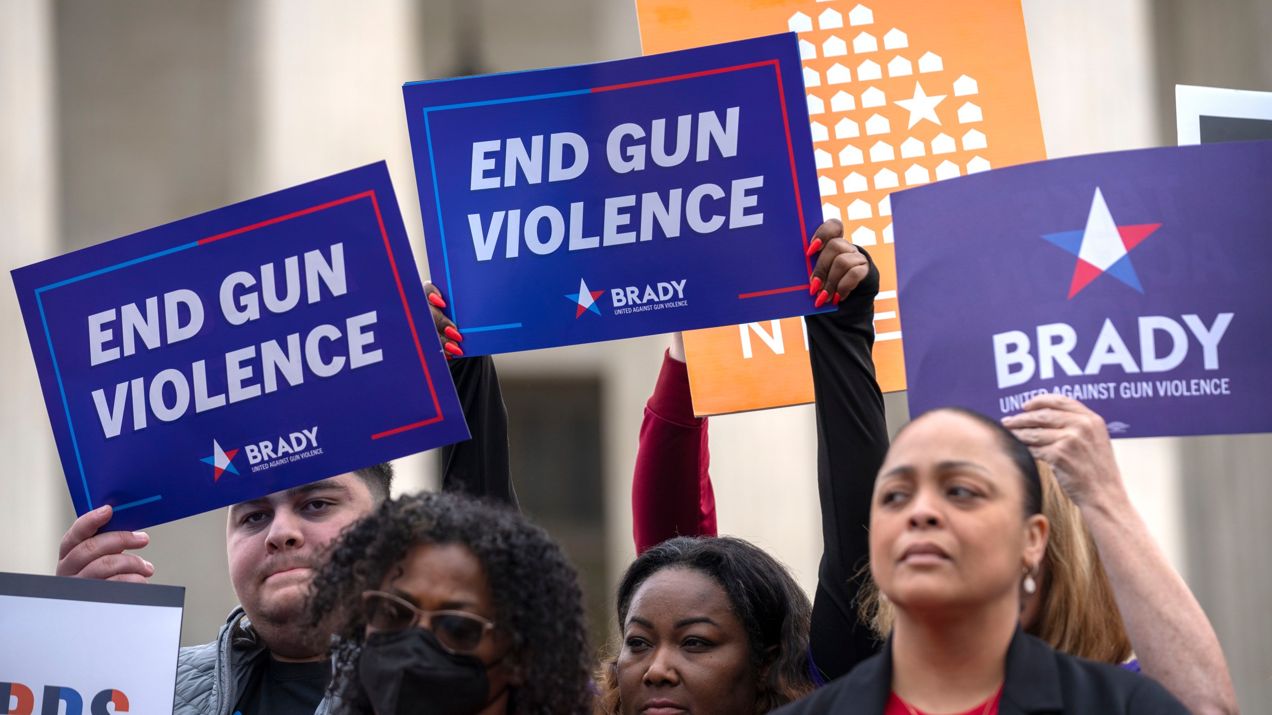 Demonstrators hold signs reading "End Gun Violence" at the Supreme Court on Tuesday, Nov. 7, 2023, in Washington. The Supreme Court is taking up a challenge to a federal law that prohibits people from having guns if they are under a court order to stay away from their spouse, partner or other family members. (AP Photo/Mark Schiefelbein)