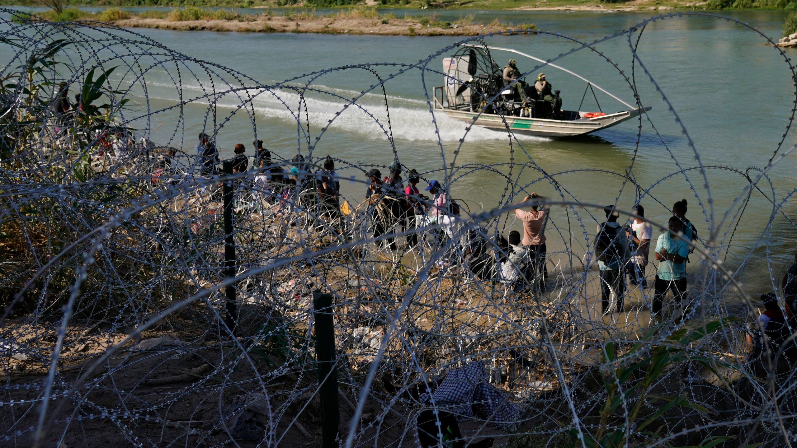 FILE - Migrants who crossed into the U.S. from Mexico are met with concertina wire along the Rio Grande, Thursday, Sept. 21, 2023, in Eagle Pass, Texas. U.S. authorities say illegal border crossings from Mexico fell 14% in October from a month earlier, following three months of big increases. The decline comes during the resumption of deportation flights to Venezuela, shortly after Venezuelans replaced Mexicans as the largest nationality appearing at the border. (AP Photo/Eric Gay, File)