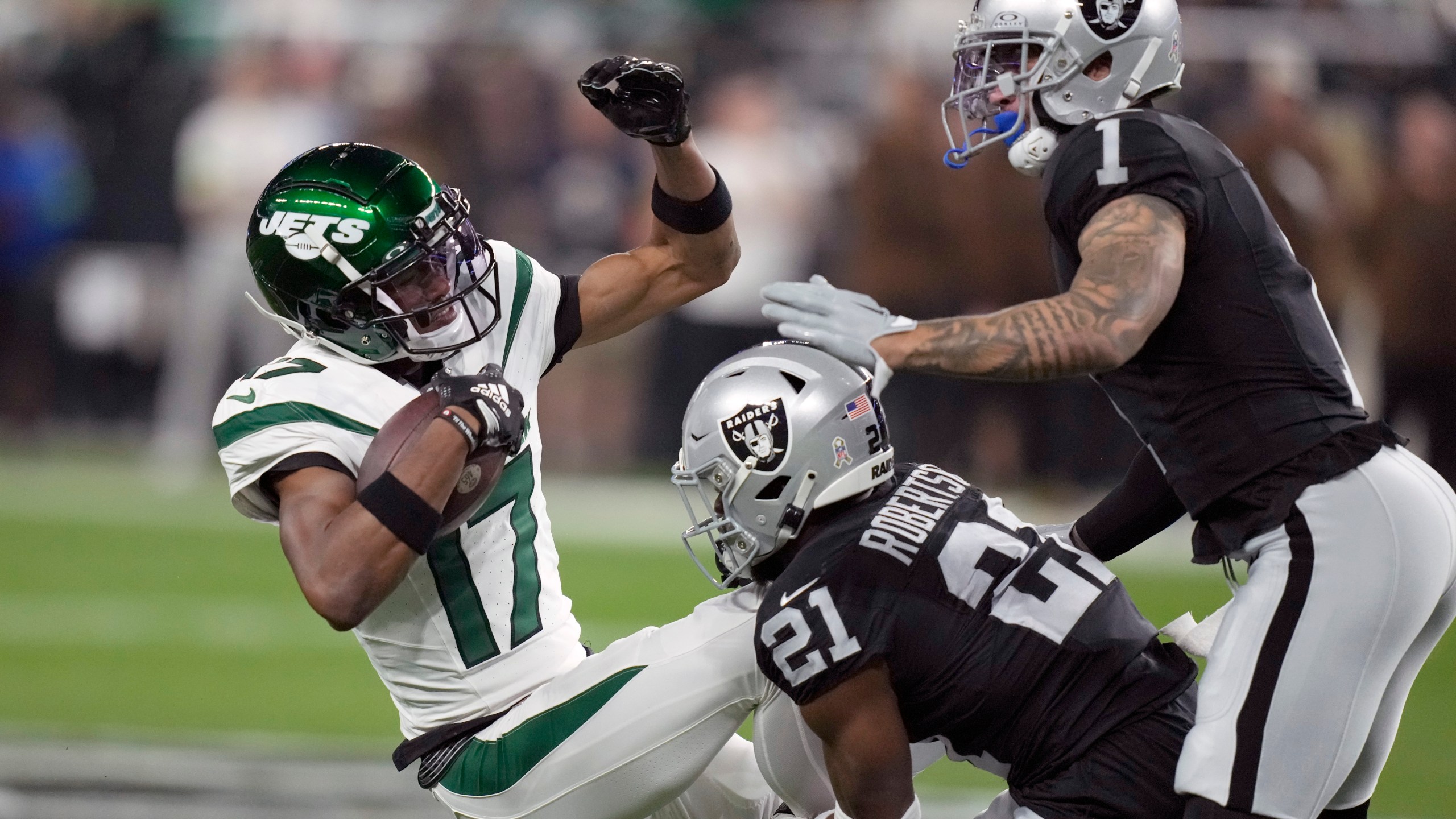 New York Jets wide receiver Garrett Wilson (17) is stopped by Las Vegas Raiders cornerback Amik Robertson (21) and safety Marcus Epps (1) after catching a pass during the first half of an NFL football game Sunday, Nov. 12, 2023, in Las Vegas. (AP Photo/John Locher)