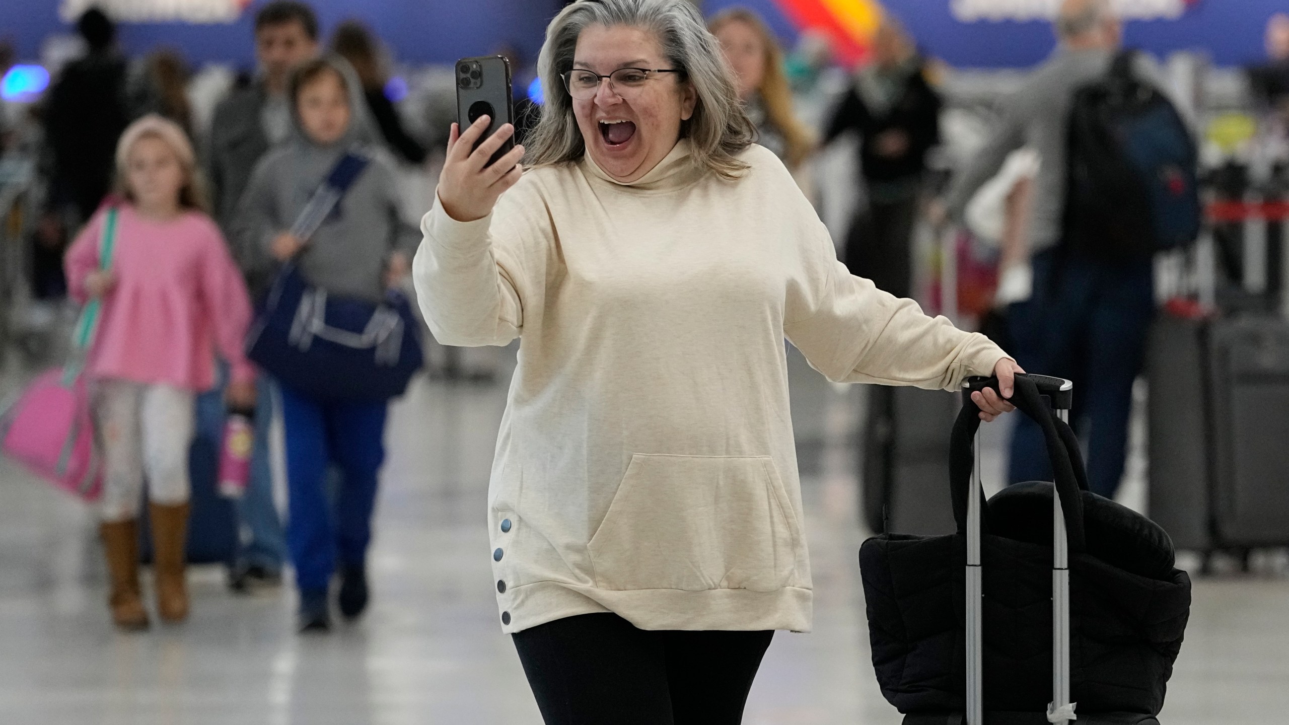 Marissa Colleluori talks to her granddaughter through FaceTime at the Nashville International Airport, Tuesday, Nov. 21, 2023, in Nashville, Tenn. before boarding her flight to Buffalo for the Thanksgiving holiday. Despite inflation and memories of past holiday travel meltdowns, millions of people are expected to hit airports and highways in record numbers over holiday. (AP Photo/George Walker IV)