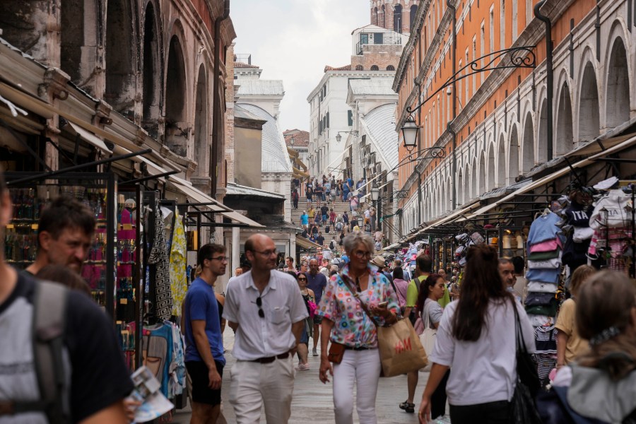 FILE -Tourists walk in a crowded street in Venice, Italy, Wednesday, Sept. 13, 2023. Venice authorities have rolled out a pilot program to charge day-trippers 5 euros ($5.45) apiece to enter the fragile lagoon city on peak weekends next year. The aim is to reduce crowds, encourage longer visits and improve the quality of life for residents. (AP Photo/Luca Bruno, File)