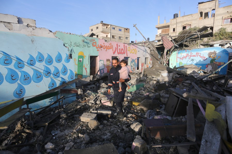 Palestinians walk by a building destroyed in Israeli bombardment overnight in Rafah, Gaza Strip, Friday, Nov. 24, 2023. (AP Photo/Hatem Ali)