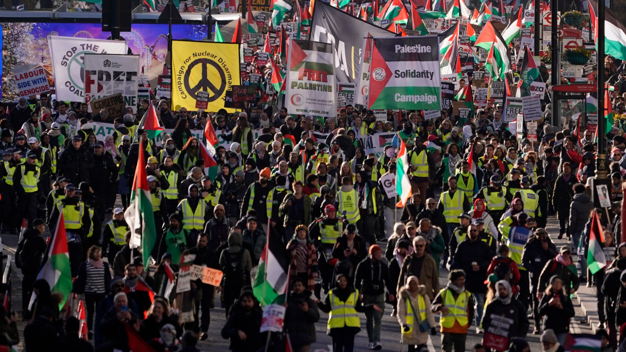 Protester hold flags and placards as they take part in a pro-Palestinian demonstration in London, Saturday, Nov. 25, 2023. (AP Photo/Alberto Pezzali)