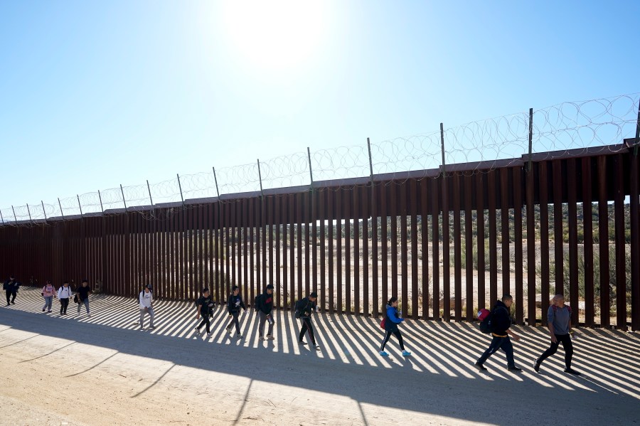 FILE - A group of people, including many from China, walk along the wall after crossing the border with Mexico to seek asylum, Tuesday, Oct. 24, 2023, near Jacumba, Calif. As Congress returns this week, Senate Republicans have made it clear they won’t support additional war aid for Ukraine unless they can pair it with border security measures. (AP Photo/Gregory Bull, File)