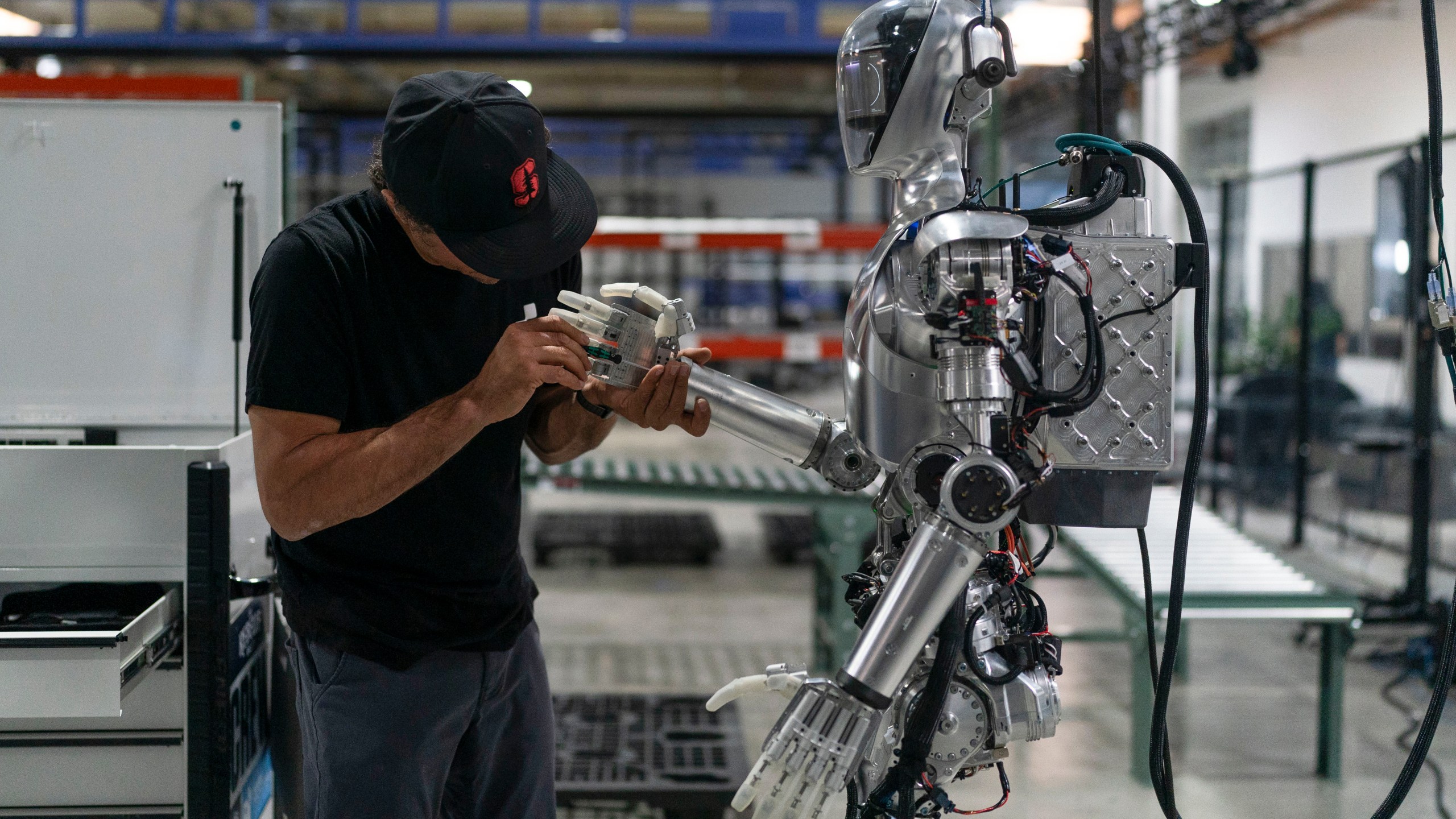 Joel Carrasco performs maintenance on humanoid robot Figure 01 at Figure AI's test facility in Sunnyvale, Calif., Tuesday, Oct. 3, 2023. Figure plans to start with a relatively simple use case, such as in a retail warehouse, but aims for a commercial robot that can be "iterated on like an iPhone" to perform multiple tasks to take up the work of humans as birth rates decline around the world. (AP Photo/Jae C. Hong)