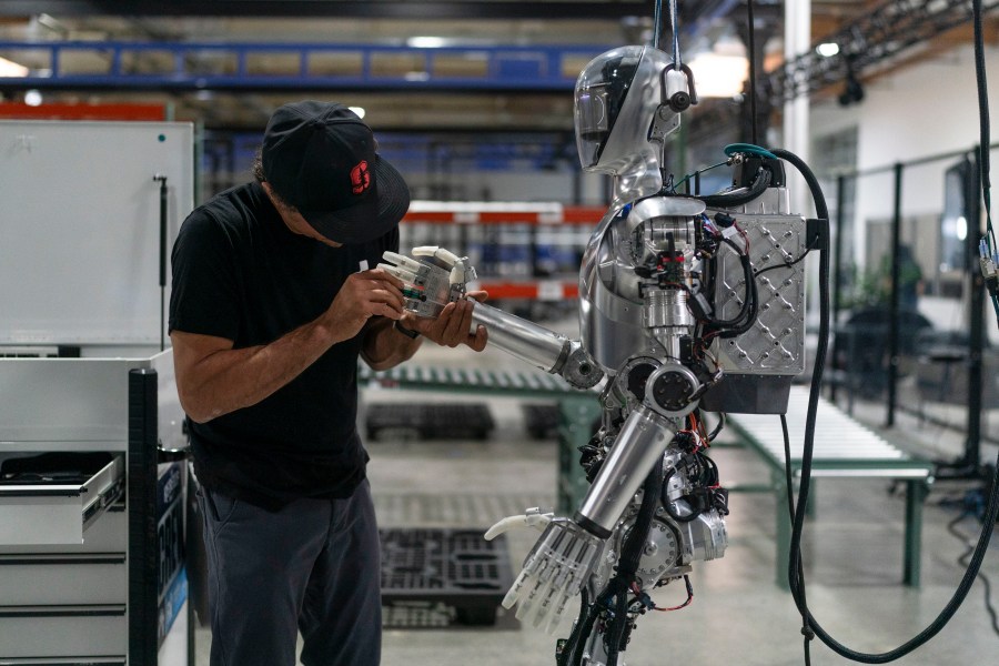 Joel Carrasco performs maintenance on humanoid robot Figure 01 at Figure AI's test facility in Sunnyvale, Calif., Tuesday, Oct. 3, 2023. Figure plans to start with a relatively simple use case, such as in a retail warehouse, but aims for a commercial robot that can be "iterated on like an iPhone" to perform multiple tasks to take up the work of humans as birth rates decline around the world. (AP Photo/Jae C. Hong)