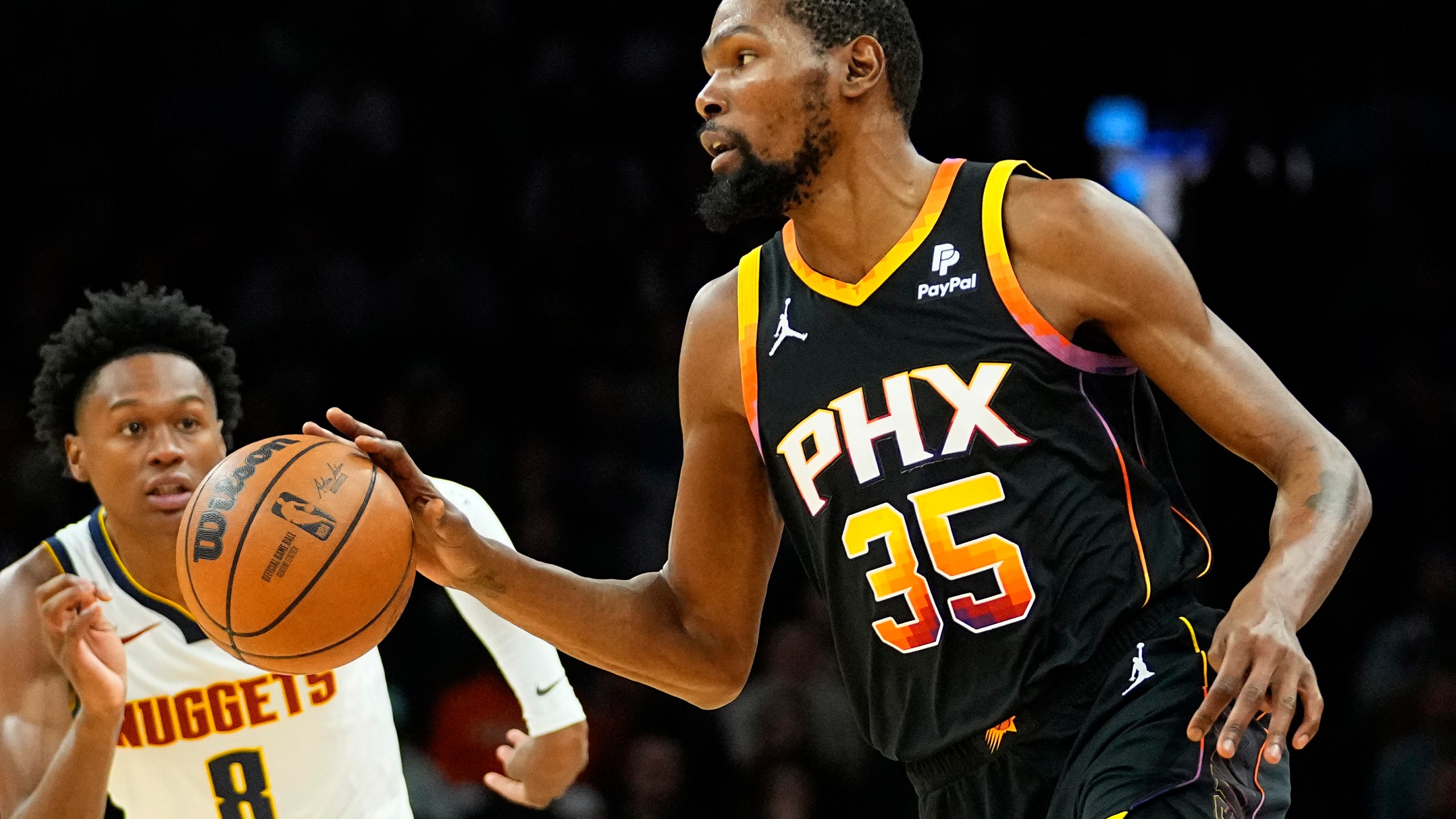 Phoenix Suns forward Kevin Durant (35) moves the ball up court as Denver Nuggets forward Peyton Watson (8) defends during the first half of an NBA basketball game, Friday, Dec. 1, 2023, in Phoenix. (AP Photo/Matt York)