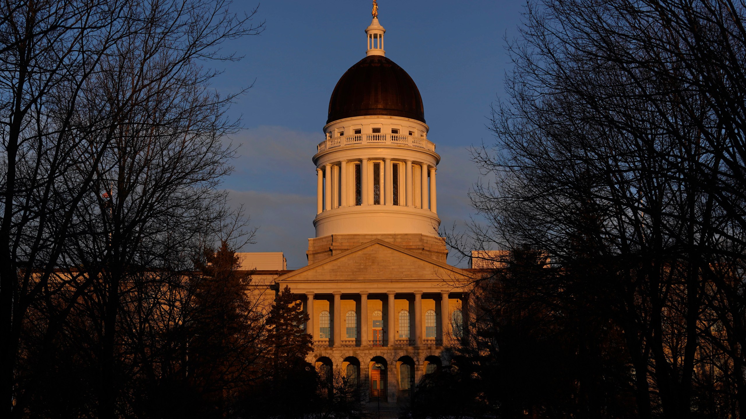 FILE - The Maine State House is seen at sunrise, March 16, 2023, in Augusta, Maine. Teachers and science advocates are voicing skepticism about a Maine proposal to update science education standards to incorporate teaching about genocide, eugenics and the Holocaust because of concerns about adequate teacher training and the nuanced nature of the material. The Maine Department of Education is performing the update as part of a review of standards that is required every five years. The proposed updates would have to ultimately be approved by a committee of the Maine Legislature. (AP Photo/Robert F. Bukaty, File)