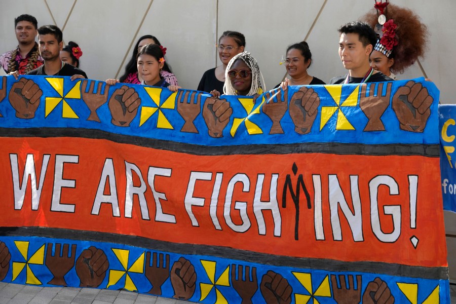 Activists hold a banner reading "we are fighting" at the COP28 U.N. Climate Summit, Friday, Dec. 8, 2023, in Dubai, United Arab Emirates. (AP Photo/Peter Dejong)