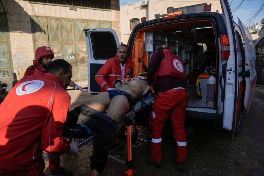 Medics evacuate a wounded Palestinian following an Israeli military raid in Faraa refugee camp, West Bank, Friday, Dec. 8, 2023. The Palestinian Health Ministry says that five Palestinians were killed when Israeli forces raided the camp prompting fighting with local militants. (AP Photo/Majdi Mohammed)