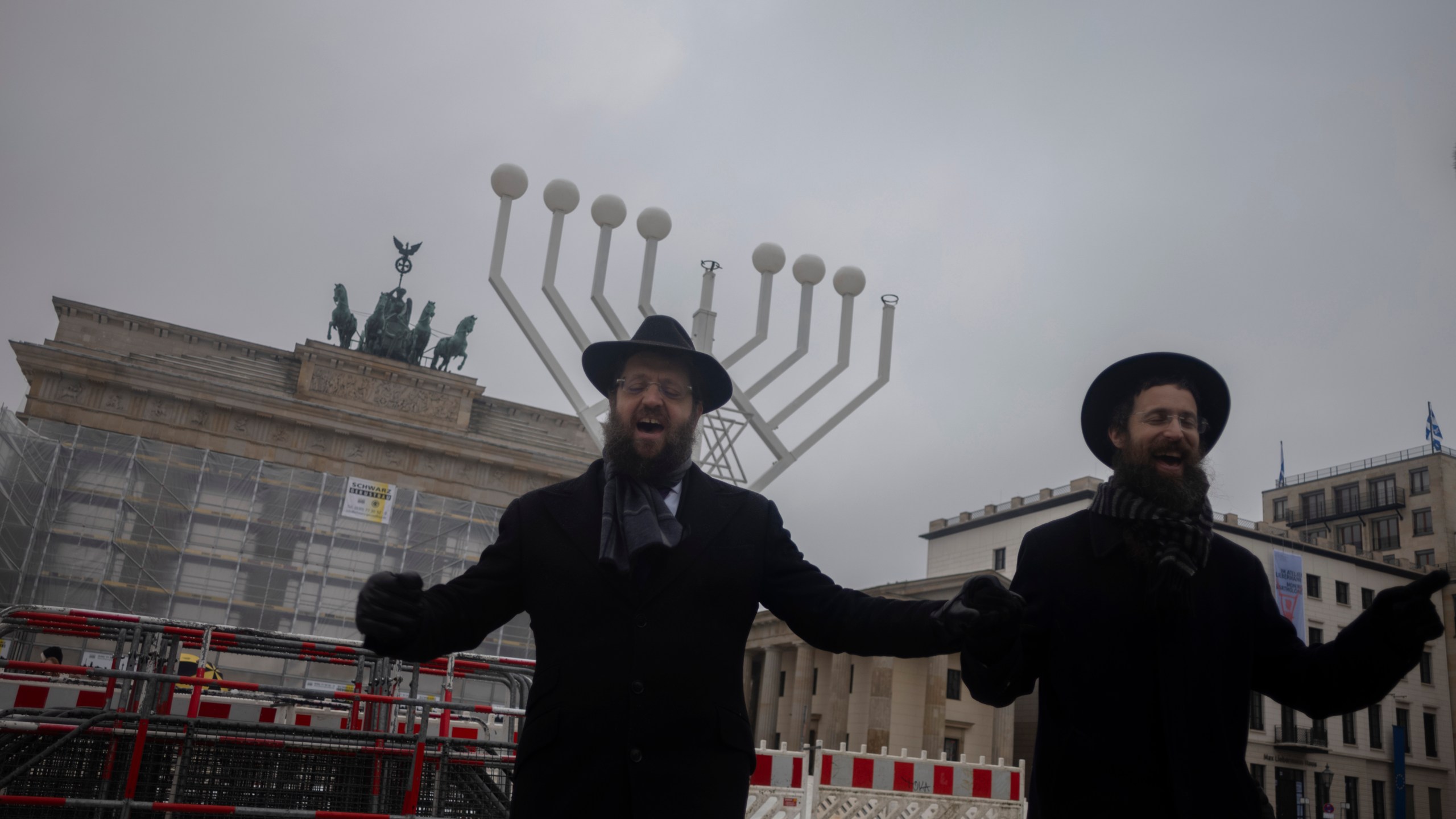 FILE - Rabbi Yehuda Teichtal, right, and Rabbi Shmuel Segal dance in front of a giant Hanukkah Menorah, after it was set up by the Jewish Chabad Educational Center ahead of the Jewish Hanukkah holiday, in front of the Brandenburg Gate at the Pariser Platz in central Berlin, Germany, Wednesday, Dec. 6, 2023. Holocaust survivors from around the globe will mark the start of the fifth day of Hanukkah together with a virtual ceremony as worries grow among Jews worldwide about the Israel-Hamas war and a spike of antisemitism in Europe, the United States and elsewhere. (AP Photo/Markus Schreiber, File)