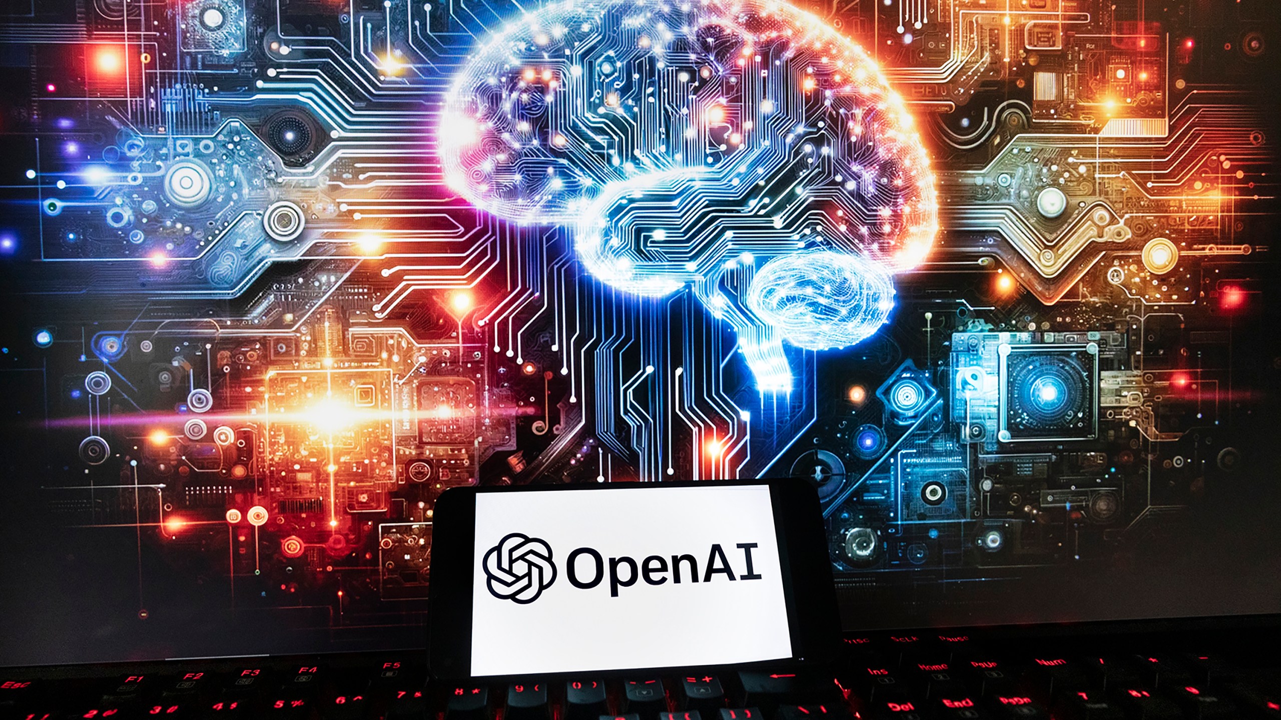 The OpenAI logo is displayed on a cell phone with an image on a computer monitor generated by ChatGPT's Dall-E text-to-image model, Friday, Dec. 8, 2023, in Boston. Europe's yearslong efforts to draw up AI guardrails have been bogged down by the recent emergence of generative AI systems like OpenAI's ChatGPT, which have dazzled the world with their ability to produce human-like work but raised fears about the risks they pose. (AP Photo/Michael Dwyer)