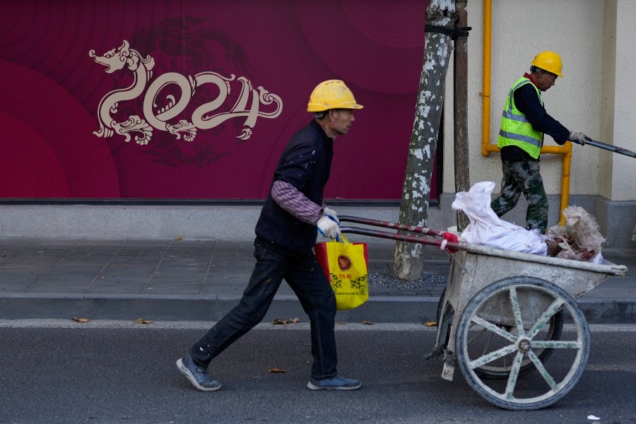 Workers push trolleys passing by under construction retail shop baring a dragon shaped 2024, the Year of the Dragon on the Chinese calendar, in Shanghai, China on Nov. 25, 2023. Chinese leaders have wrapped up a two-day annual meeting to set economic priorities for the coming year, the official Xinhua News Agency reported Tuesday, Dec. 12, 2023 without giving details of what was decided. (AP Photo/Andy Wong)