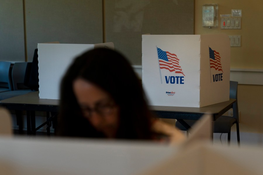 FILE - A voter in the foreground casts her ballots during the Republican primary election in Wilson, Wyo., Aug. 16, 2022. Relatively few Americans are excited about a potential rematch of the 2020 election between President Joe Biden and Donald Trump. But more Republicans would be happy to have Trump as their nominee than Democrats would be with Biden. That's according to a new poll from The Associated Press-NORC Center for Public Affairs Research. (AP Photo/Jae C. Hong, File)