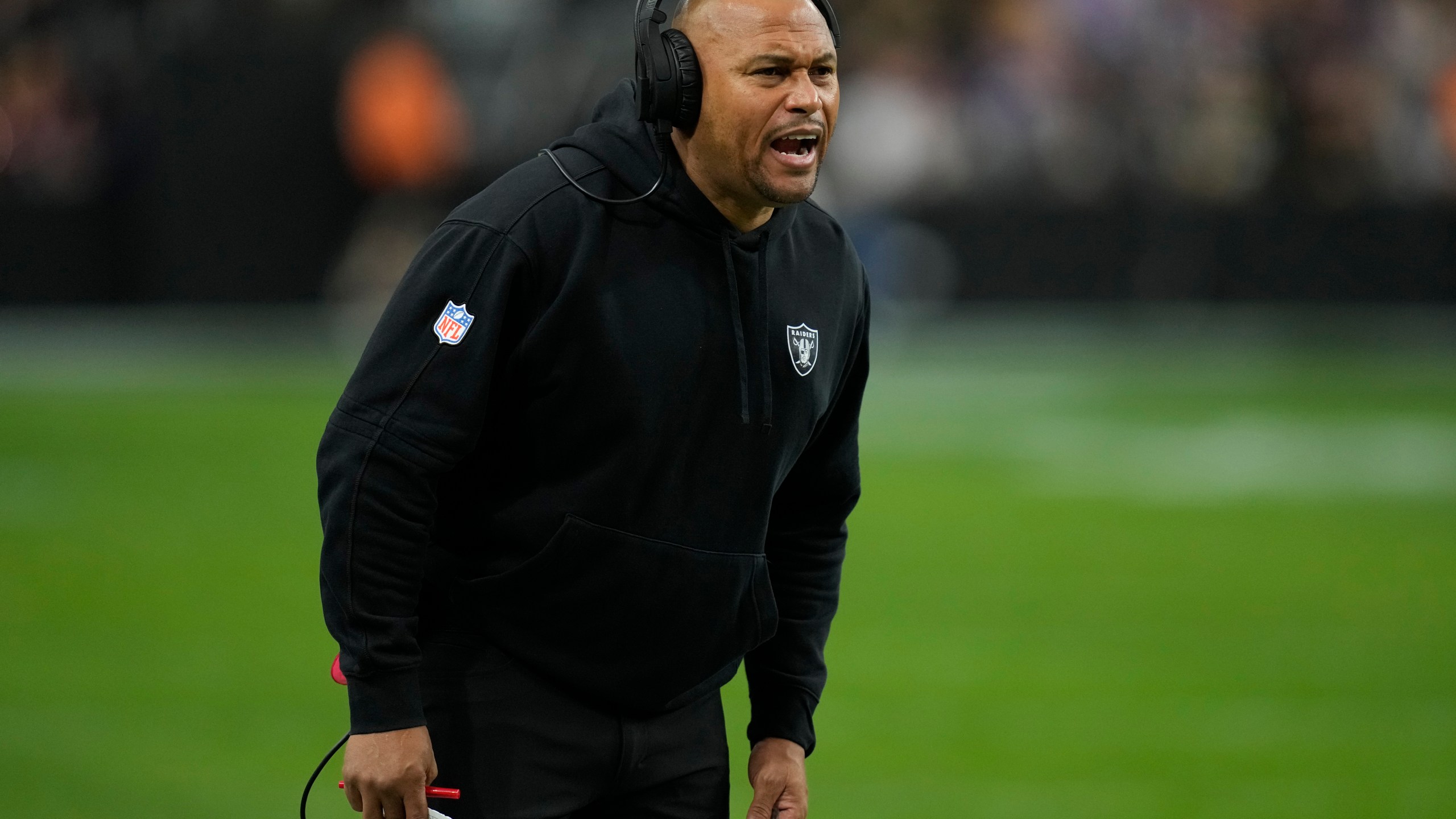 Las Vegas Raiders interim head coach Antonio Pierce makes a call during the first half of an NFL football game against the Minnesota Vikings, Sunday, Dec. 10, 2023, in Las Vegas. (AP Photo/John Locher)