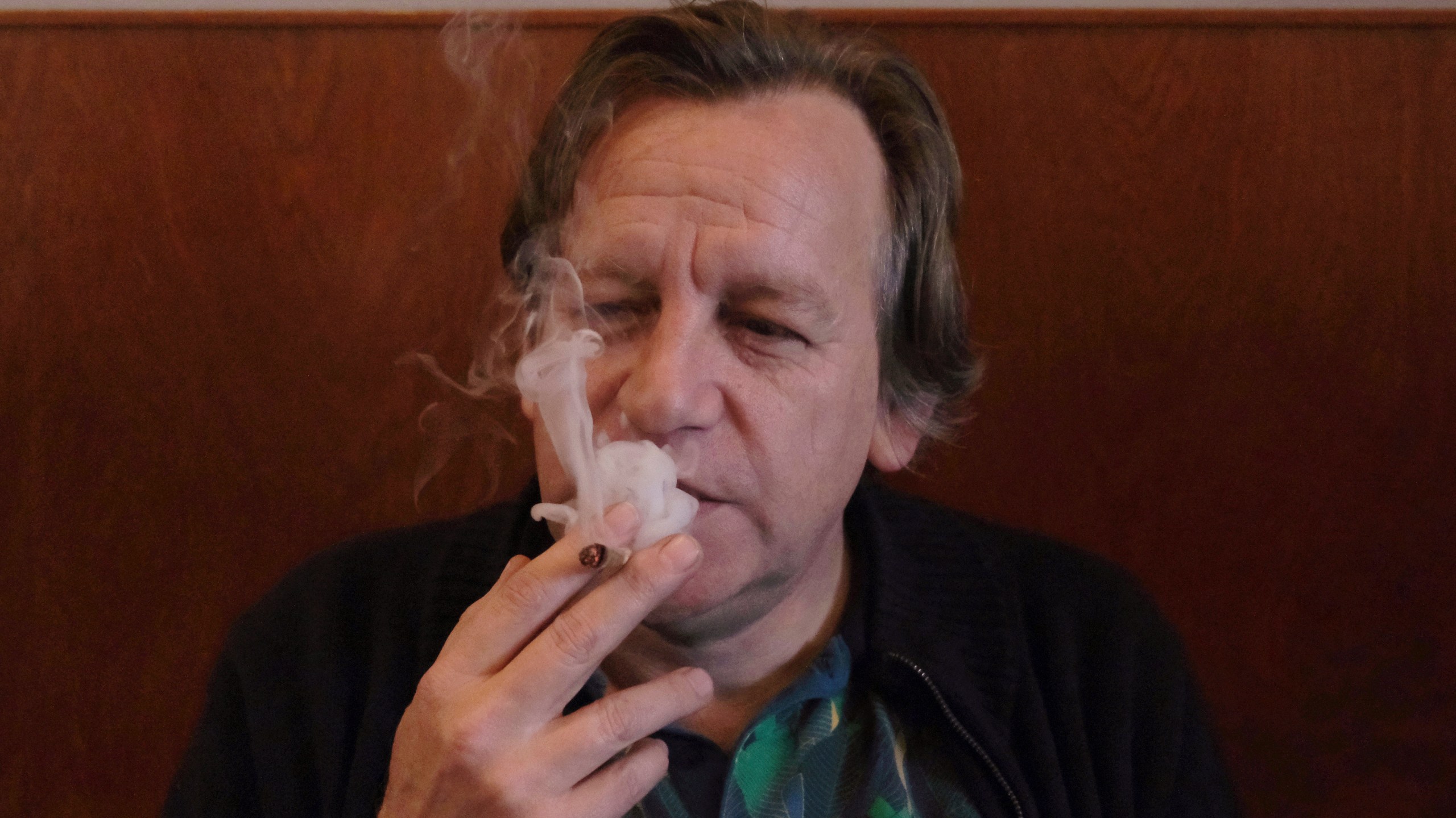 Derrick Bergman, chairman of the Union for the Abolition of Cannabis Prohibition, smokes a marijuana cigarette in coffeeshop De Baron in Breda, Netherlands, on Friday, Dec. 15, 2023. Bergman was at the coffeeshop to mark the start of a new experiment with legally grown weed going on sale in two Dutch cities. (AP Photo/Mike Corder)