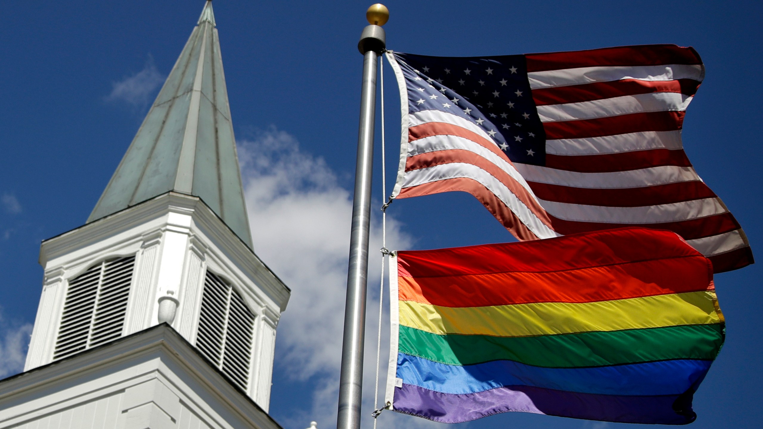 FILE - A gay pride rainbow flag flies along with the U.S. flag in front of the Asbury United Methodist Church in Prairie Village, Kan., on April 19, 2019. A quarter of U.S. congregations in the United Methodist Church have received permission to leave the denomination during a five-year window, closing in December 2023, that authorized departures for congregations over disputes involving the church's LGBTQ-related policies. (AP Photo/Charlie Riedel, File)