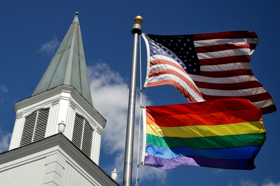 FILE - A gay pride rainbow flag flies along with the U.S. flag in front of the Asbury United Methodist Church in Prairie Village, Kan., on April 19, 2019. A quarter of U.S. congregations in the United Methodist Church have received permission to leave the denomination during a five-year window, closing in December 2023, that authorized departures for congregations over disputes involving the church's LGBTQ-related policies. (AP Photo/Charlie Riedel, File)