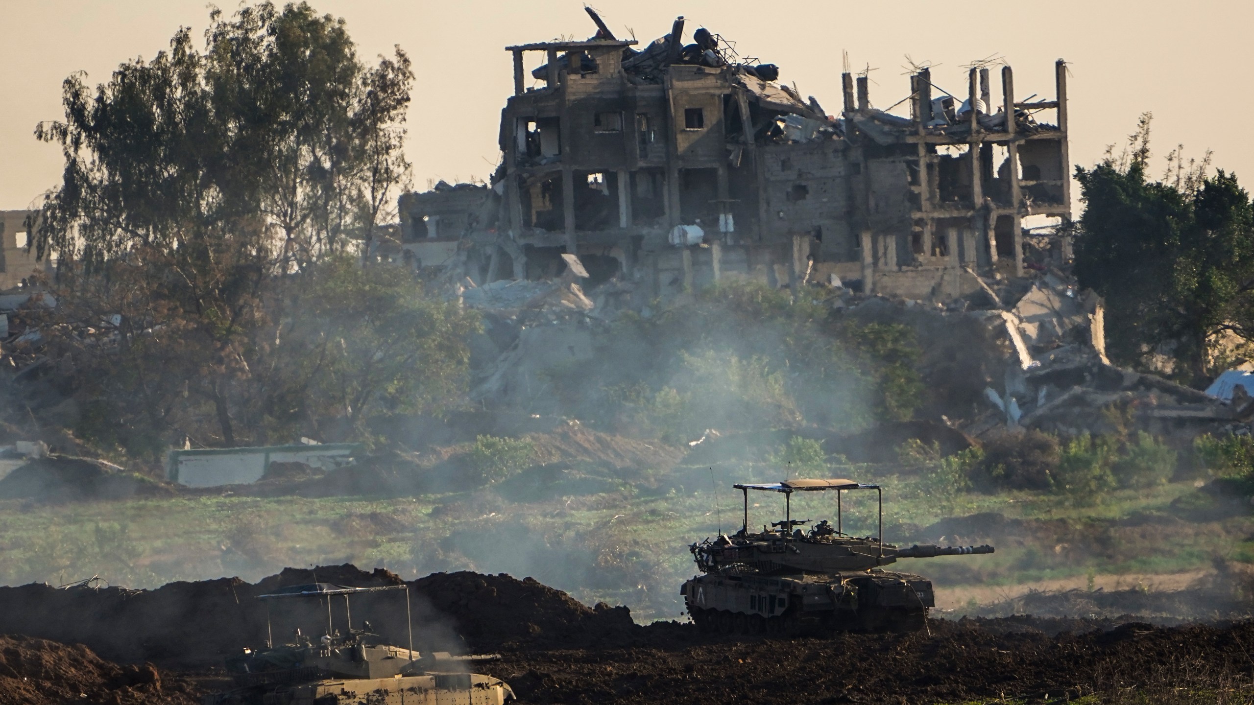 Israeli tanks are seen next to a destroyed building during a ground operation in the northern Gaza Strip, Friday, Dec. 15, 2023. The army is battling Palestinian militants across Gaza in the war ignited by Hamas' Oct. 7 attack on Israel. (AP Photo/Ariel Schalit)