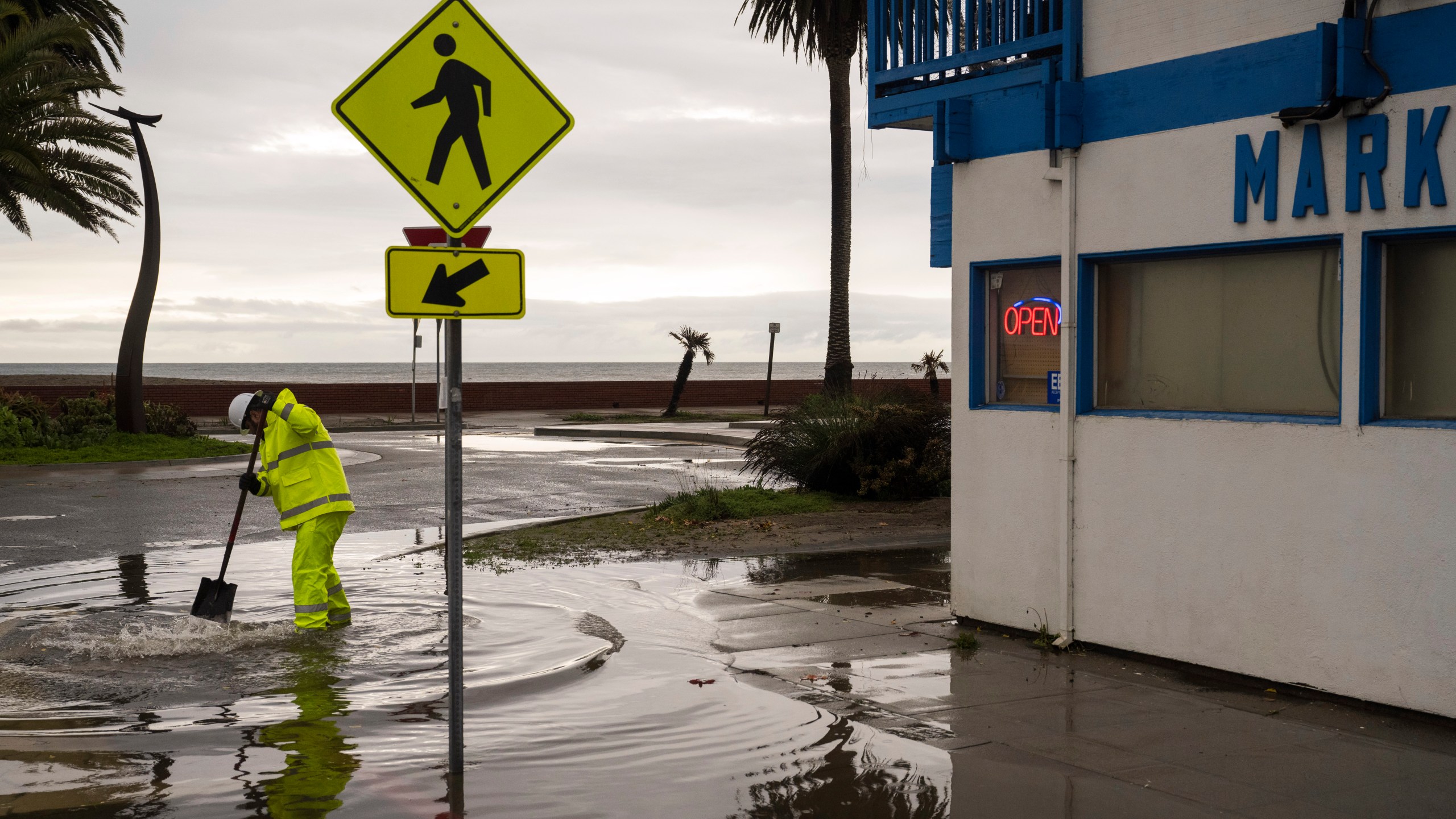 A Santa Cruz County public works employee clears a storm drain in the Rio Del Mar neighborhood of Aptos, Calif., Wednesday, Dec. 20, 2023 (AP Photo/Nic Coury)