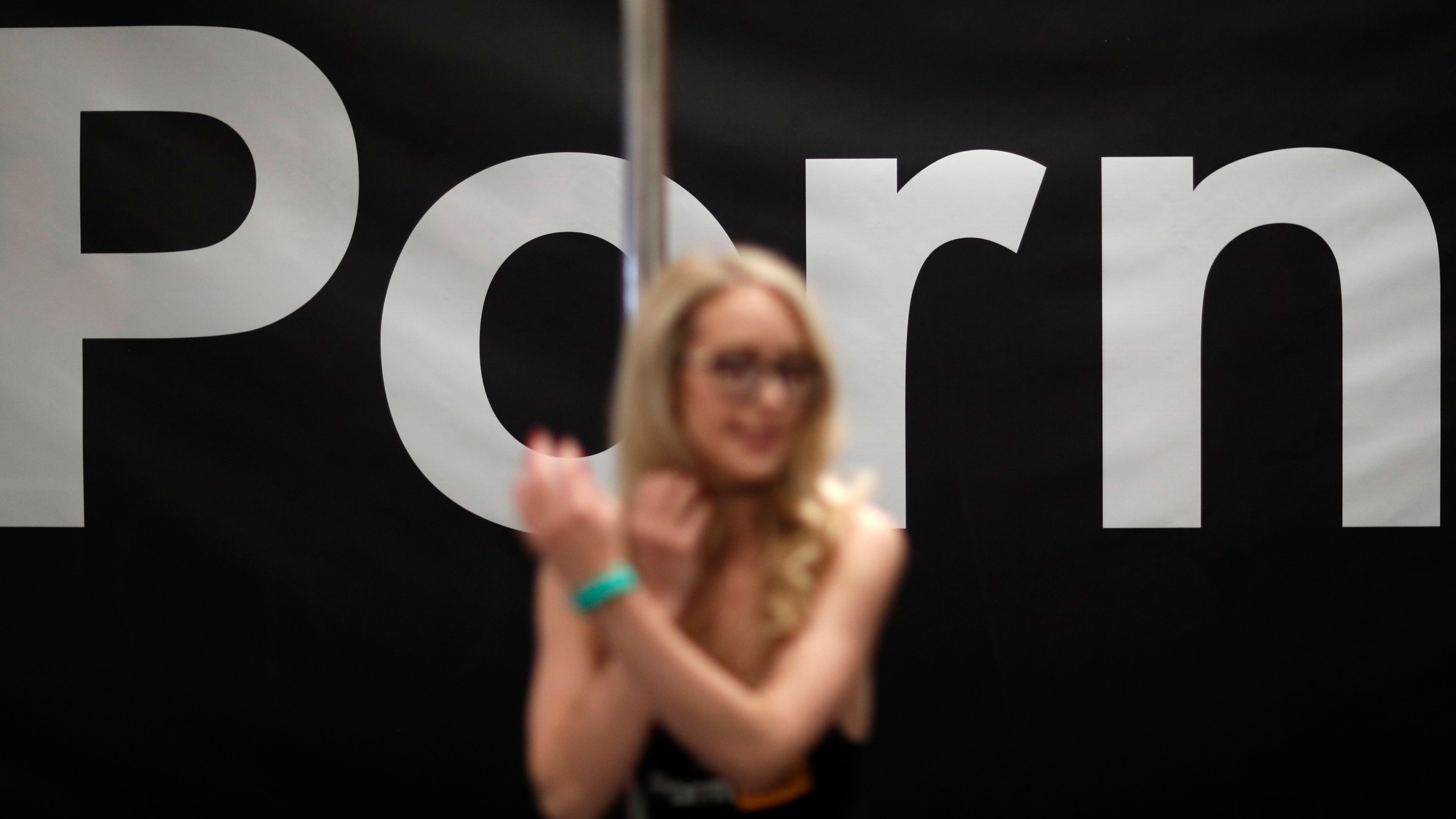 FILE - Porn actress Ginger Banks stands in the Pornhub booth during the AVN Adult Entertainment Expo, Wednesday, Jan. 24, 2018, in Las Vegas. The owner of Pornhub, one of the world’s largest adult content websites, has admitted to profiting from sex trafficking and agreed to make payments to women whose videos were posted without their consent, federal prosecutors in New York announced Thursday, Dec. 21, 2023. (AP Photo/John Locher, File)