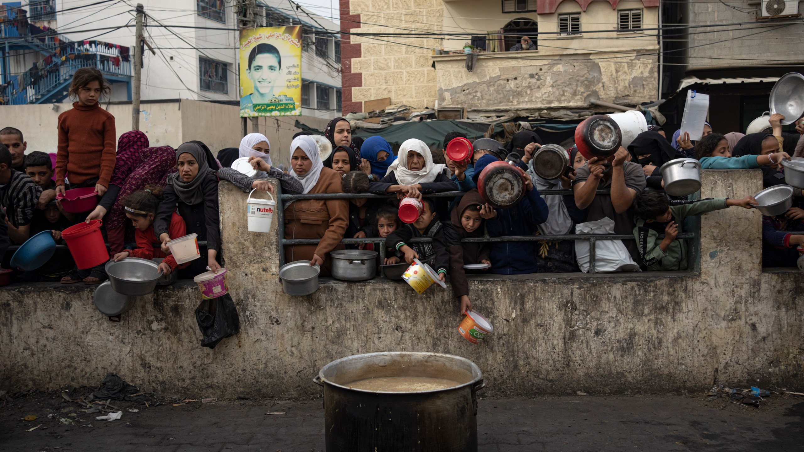 Palestinians line up for a free meal in Rafah, Gaza Strip, Thursday, Dec. 21, 2023. International aid agencies say Gaza is suffering from shortages of food, medicine and other basic supplies as a result of the two and a half month war between Israel and Hamas. (AP Photo/Fatima Shbair)