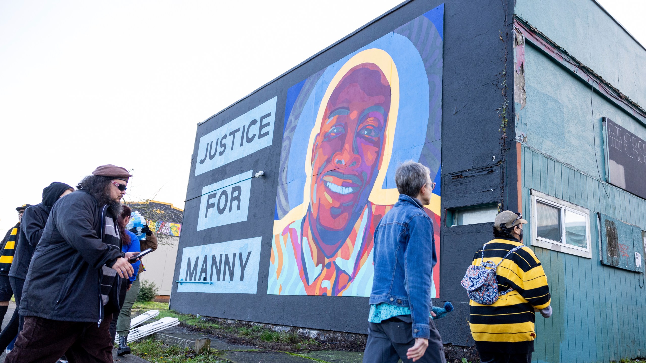 Protestors walk by a mural of Manny Ellis after the verdict is read during the trial of three Tacoma Police officers in the killing of Manny Ellis, at Pierce County Superior Court, Thursday, Dec. 21, 2023, in Tacoma, Wash. A jury cleared three Washington state police officers of all criminal charges Thursday, Dec. 21, 2023 in the 2020 death of Manuel Ellis, a Black man who was shocked, beaten and restrained face down on a Tacoma sidewalk as he pleaded for breath.. (AP Photo/Maddy Grassy)