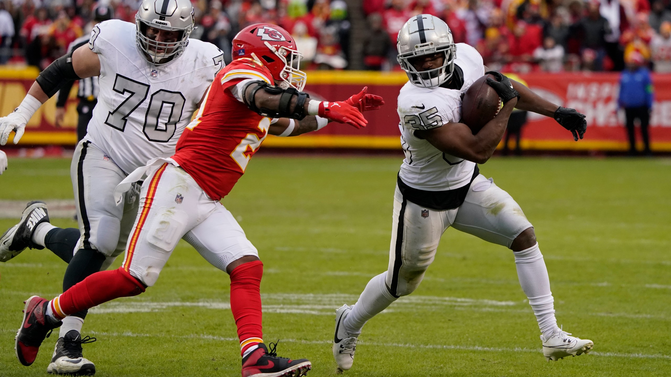 Las Vegas Raiders running back Zamir White (35) runs with the ball as Kansas City Chiefs safety Mike Edwards defends and Raiders guard Greg Van Roten looks on during the second half of an NFL football game Monday, Dec. 25, 2023, in Kansas City, Mo. (AP Photo/Ed Zurga)