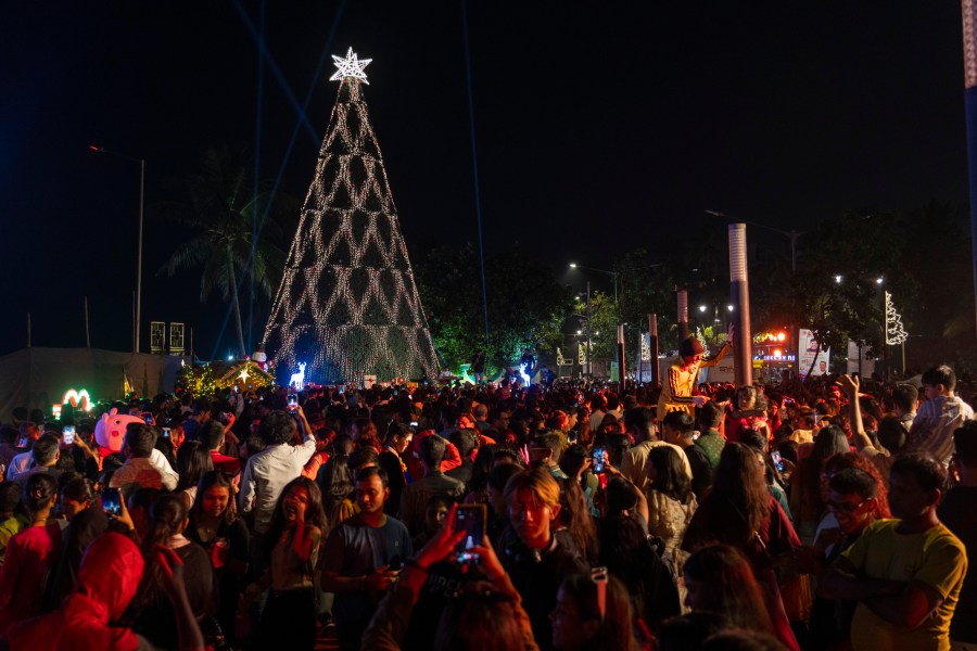 People crowd in front of a decorated Christmas tree at a promenade on the eve of Christmas in Mumbai, India, Sunday, Dec. 24, 2023. Although Christians comprise only two percent of the population Christmas is a national holiday and is observed across the country as an occasion to celebrate. (AP Photo/Rafiq Maqbool)