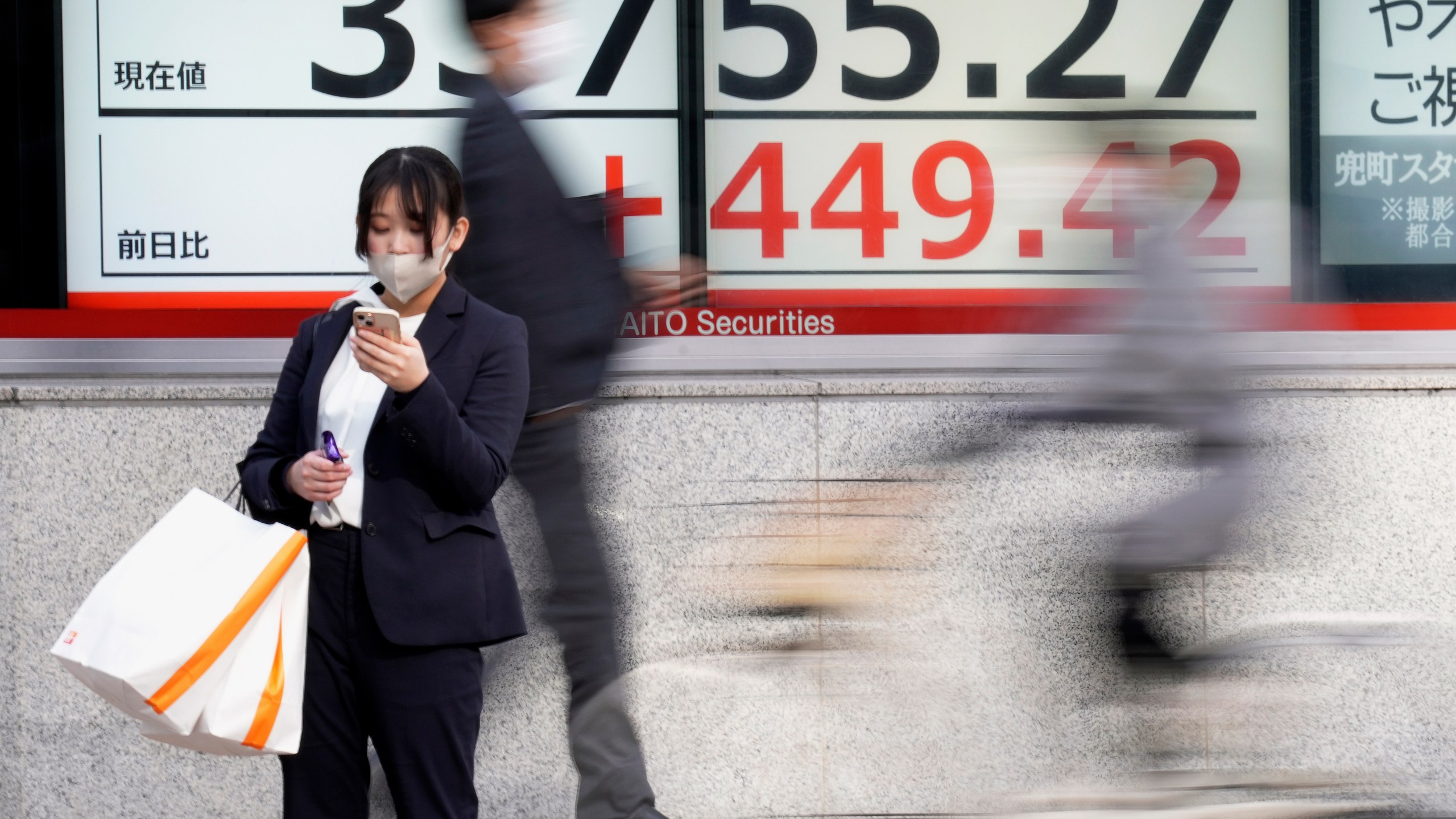 FILE - A person stands in front of an electronic stock board showing Japan's Nikkei 225 index at a securities firm on Dec. 27, 2023, in Tokyo. Asian shares were mixed in muted trading on Friday, Dec. 29, the last trading day of the year, with some regional markets logging solid gains in 2023 while many sagged.(AP Photo/Eugene Hoshiko, File)